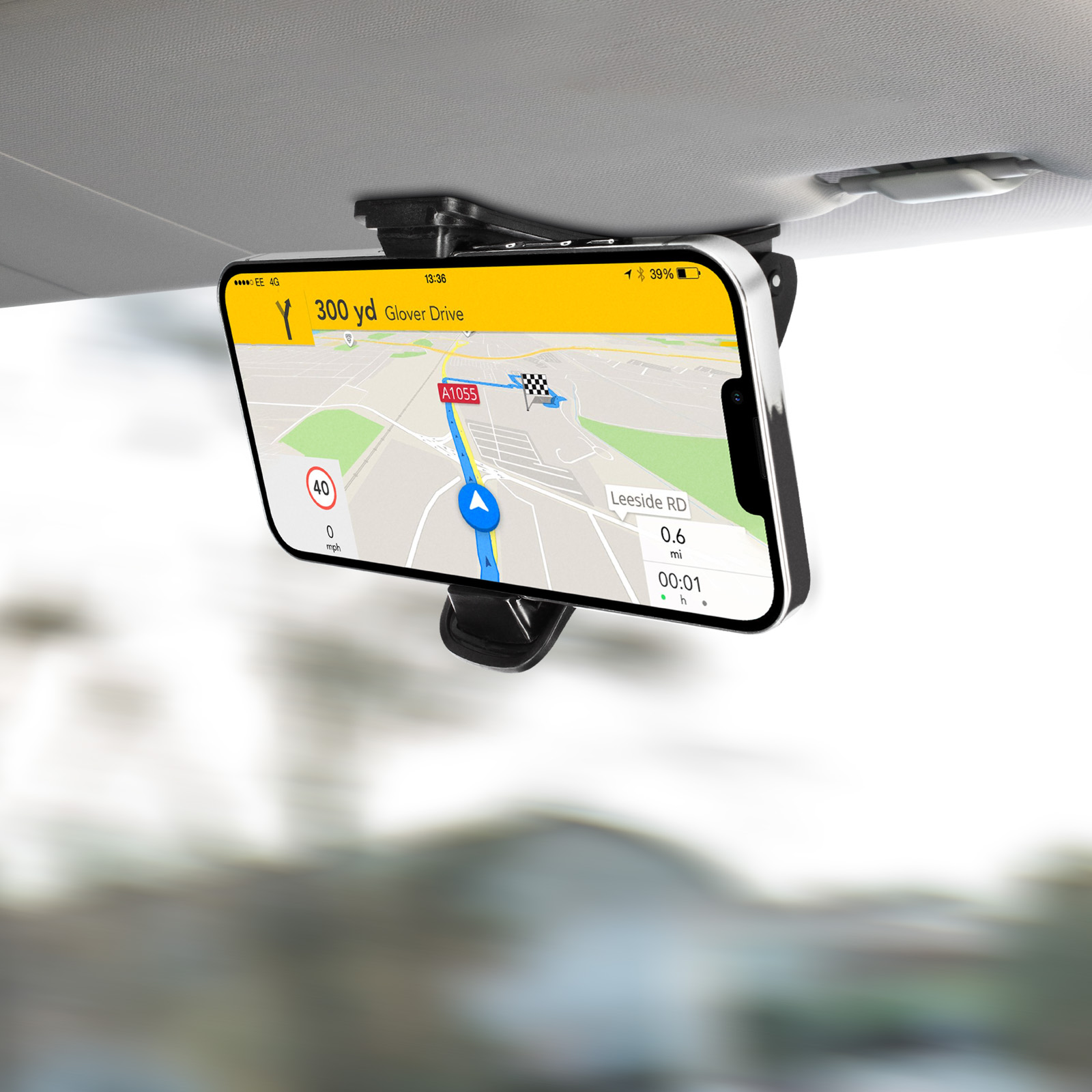 Telefon mit Navigations-App an der Sonnenblende des Autos befestigt. Straße und Stadtbild sichtbar.