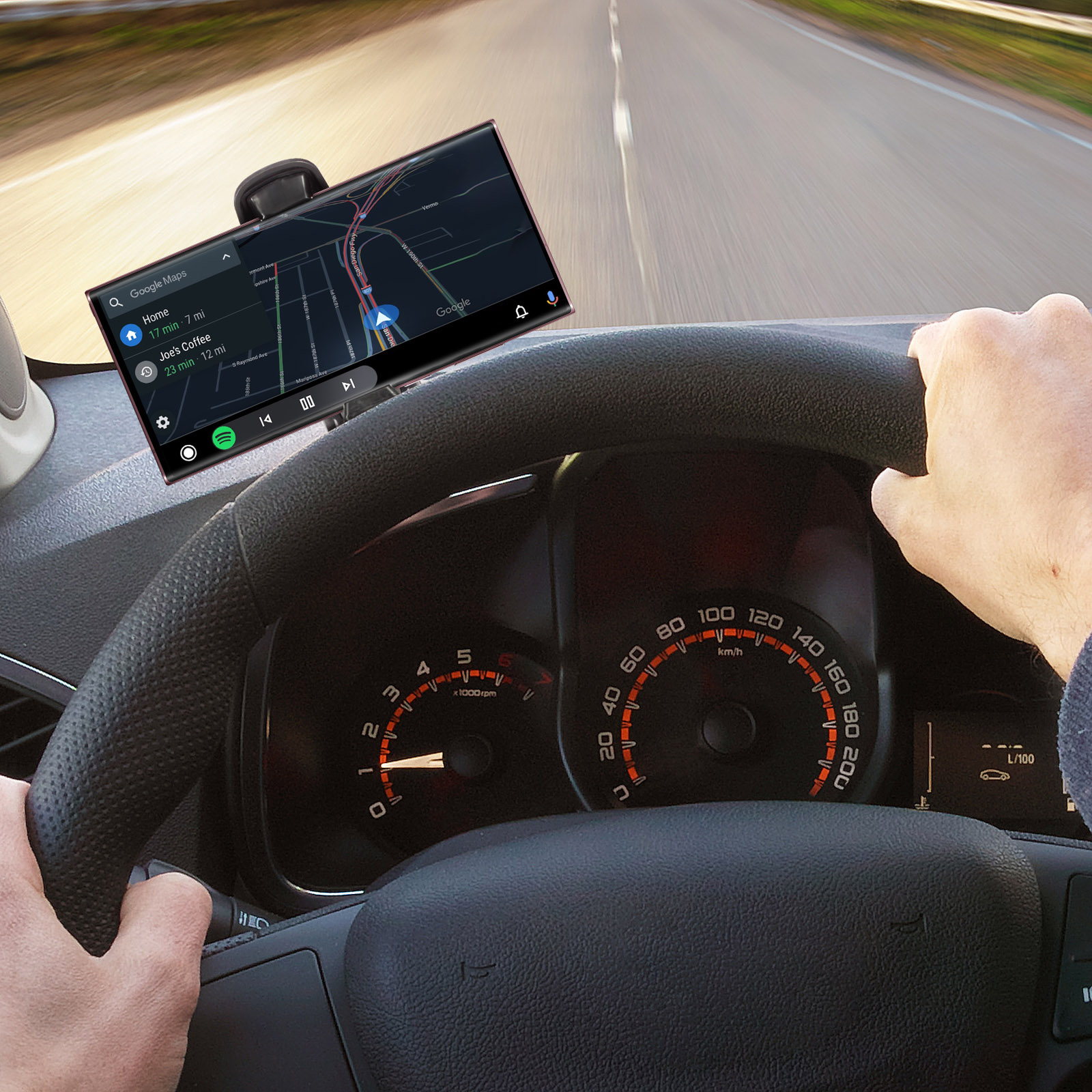 Ein auf dem Armaturenbrett montiertes Telefon mit Google Maps, Spotify. Der Fahrer hält das Lenkrad.