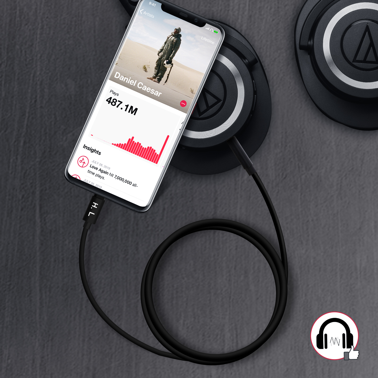 Un teléfono reproduciendo música, conectado a auriculares. Un cable negro conecta el teléfono a los auriculares.