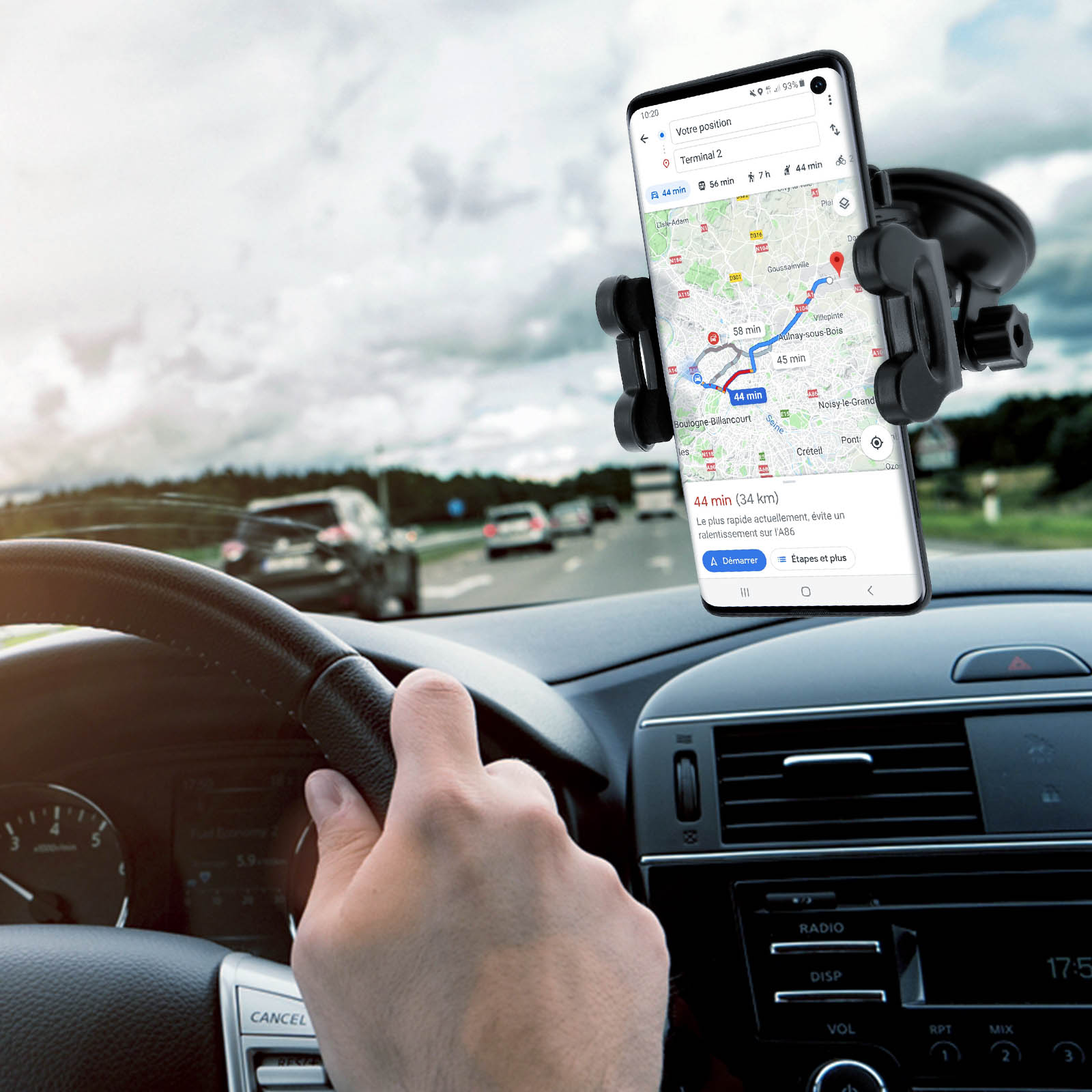 Ein Telefon mit Karte im Auto. Die Hände des Fahrers sind am Lenkrad.