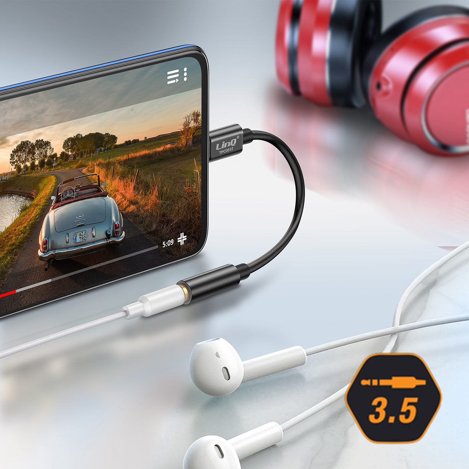 Uno smartphone mostra un video di un'auto su una strada, collegato alle cuffie tramite un adattatore nero.