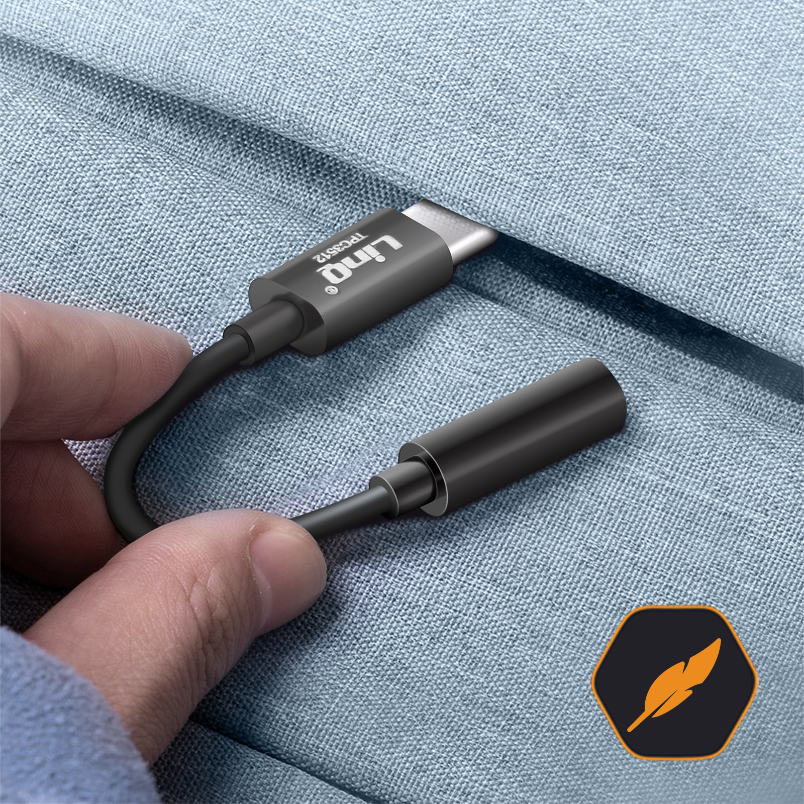 Adattatore audio da USB-C a 3,5 mm nero tenuto in mano su sfondo di tessuto blu.