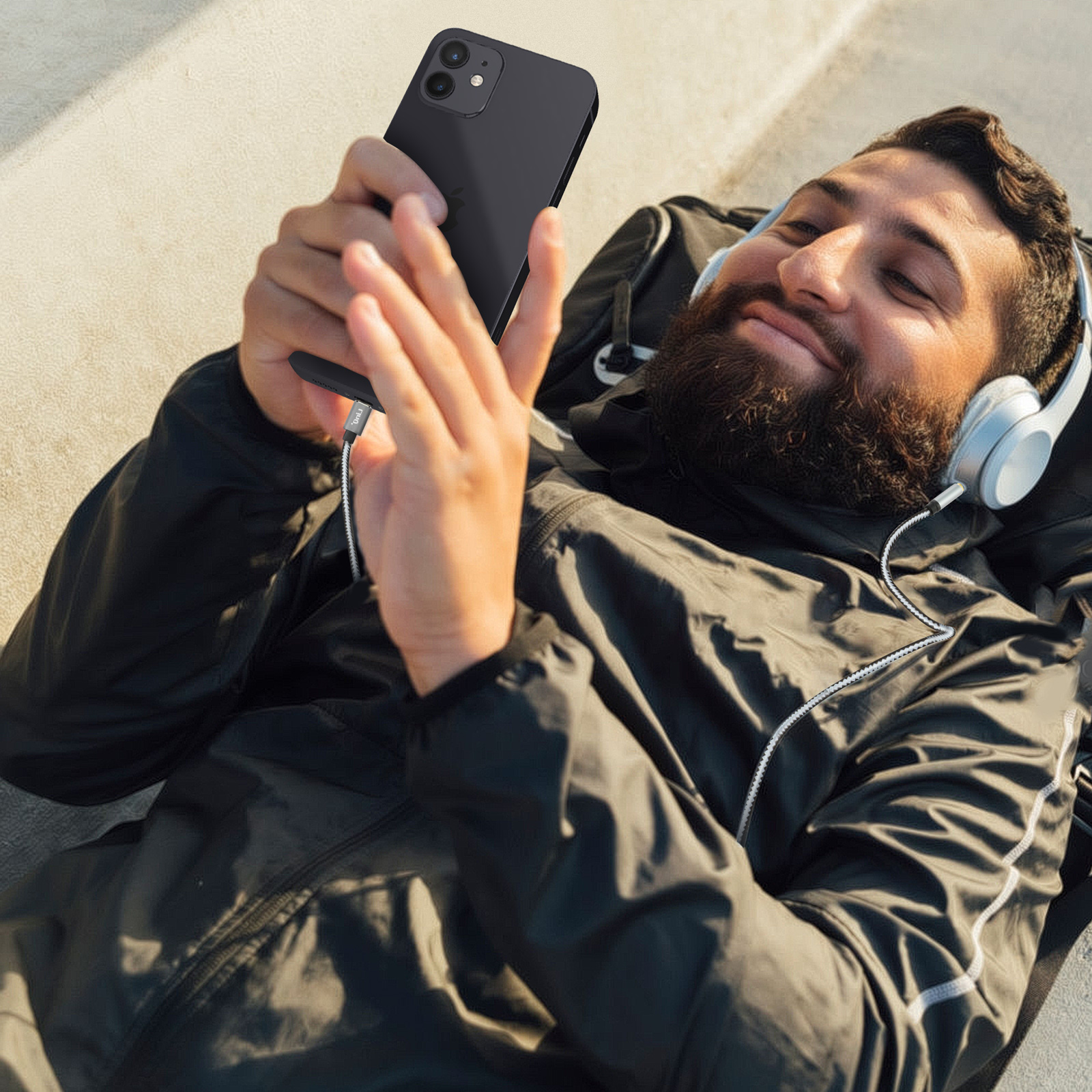 Un hombre está acostado, usando un teléfono con auriculares.
