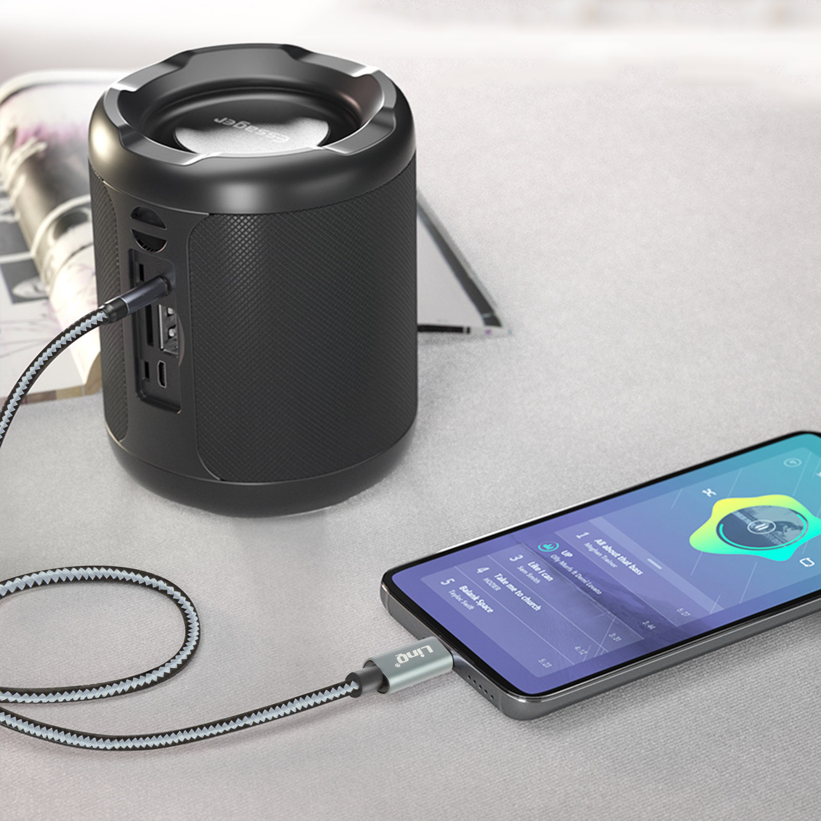 Teléfono y altavoz conectados con un cable sobre un escritorio.