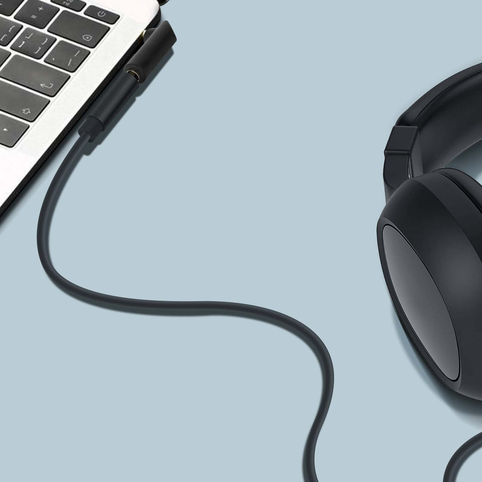 Auriculares negros y un portátil con un conector para auriculares negro. El fondo es azul.