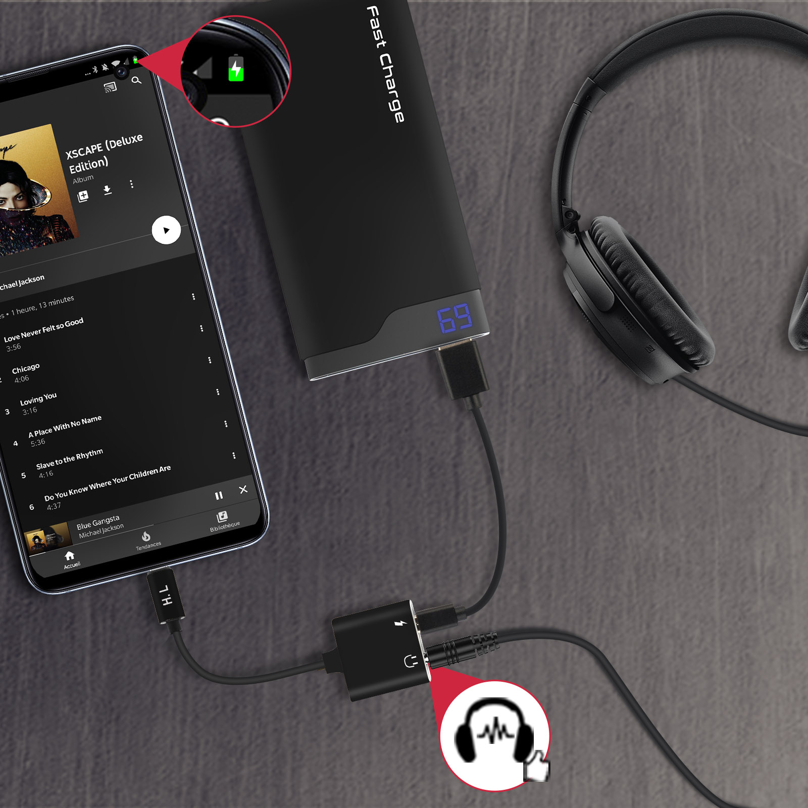 Un teléfono negro está conectado a un banco de energía negro, unos auriculares y un divisor. El teléfono muestra música.