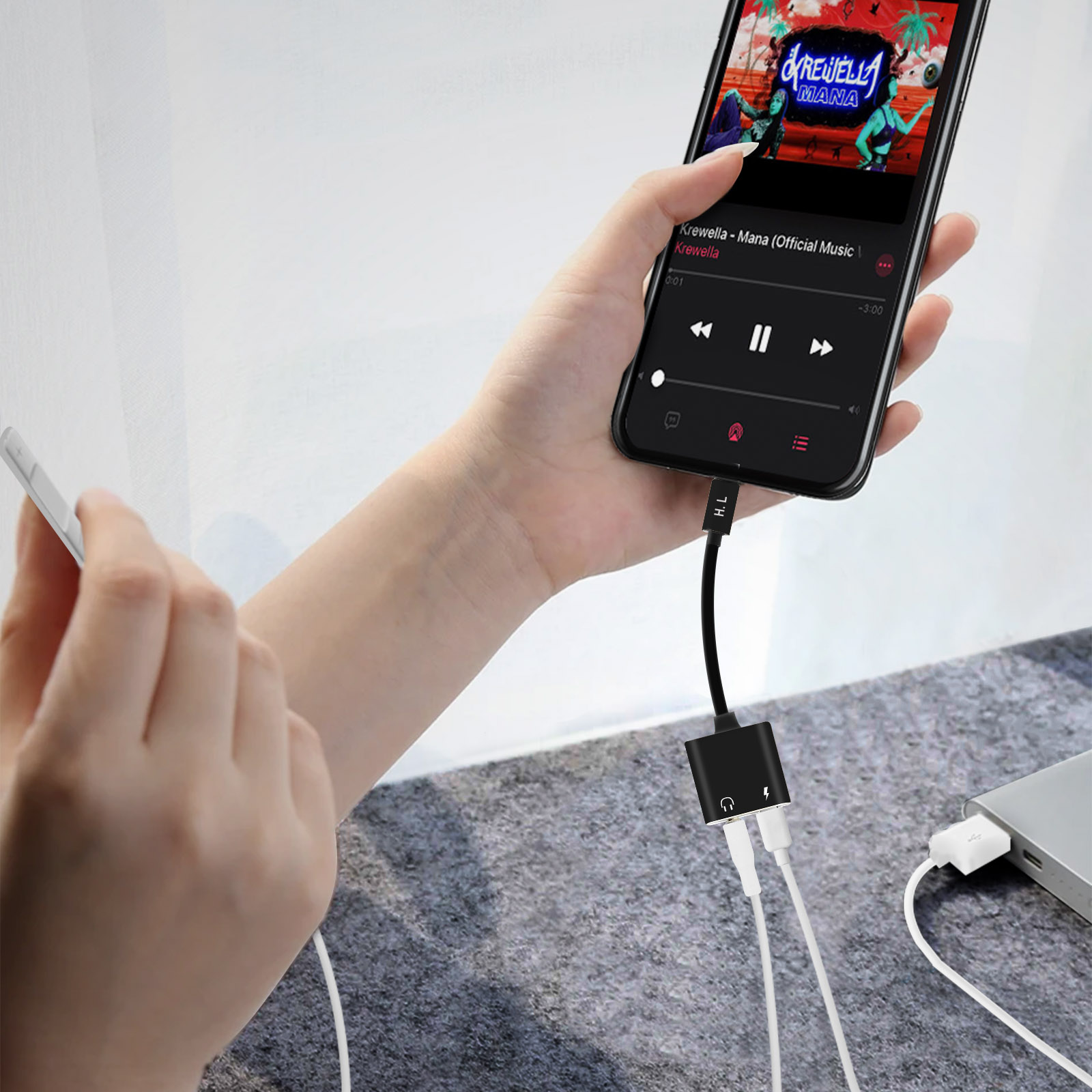 Un teléfono con un adaptador y auriculares conectados. La pantalla muestra una interfaz de aplicación de música.
