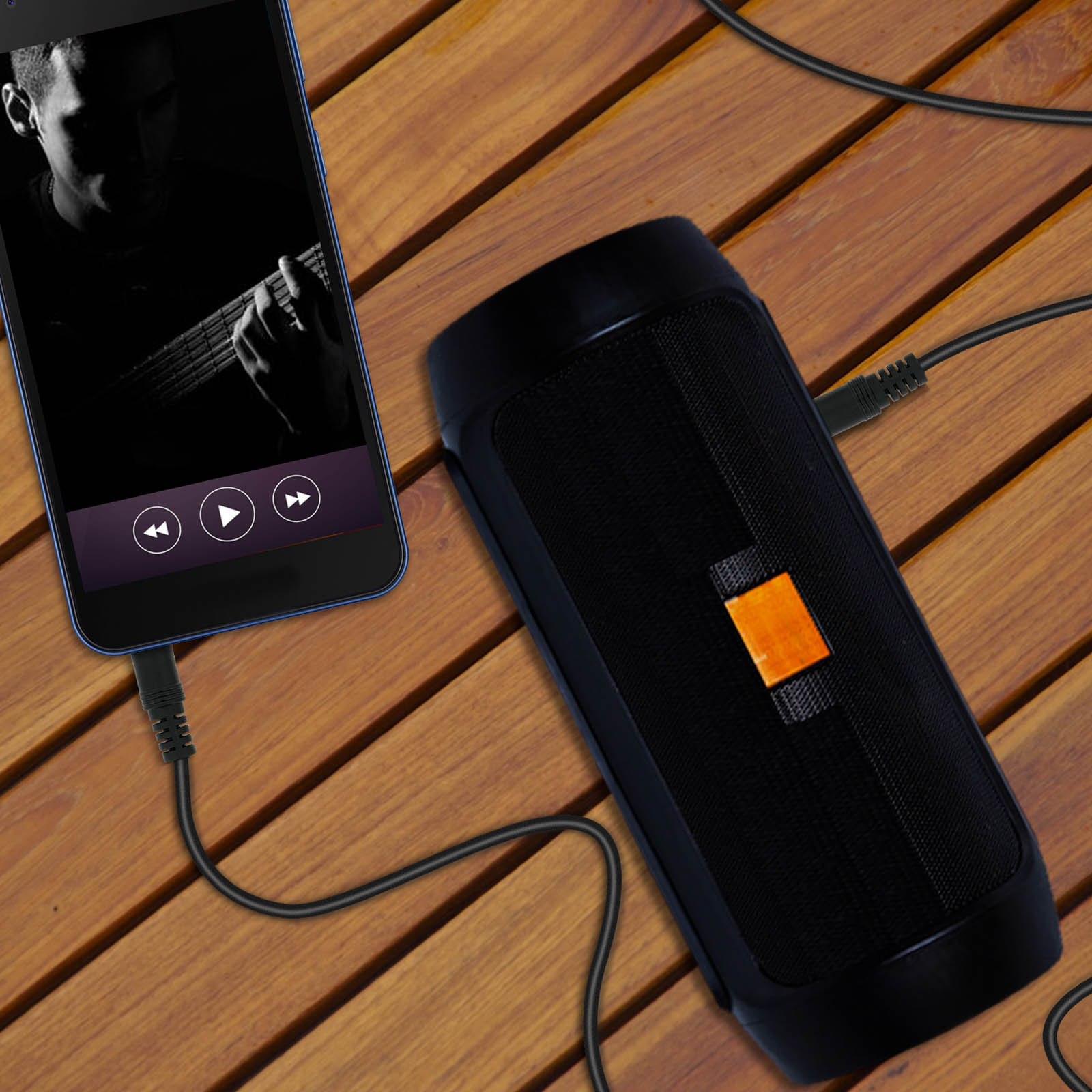 Un smartphone reproduce música, conectado a un altavoz negro por cable. Silueta de guitarrista en pantalla.
