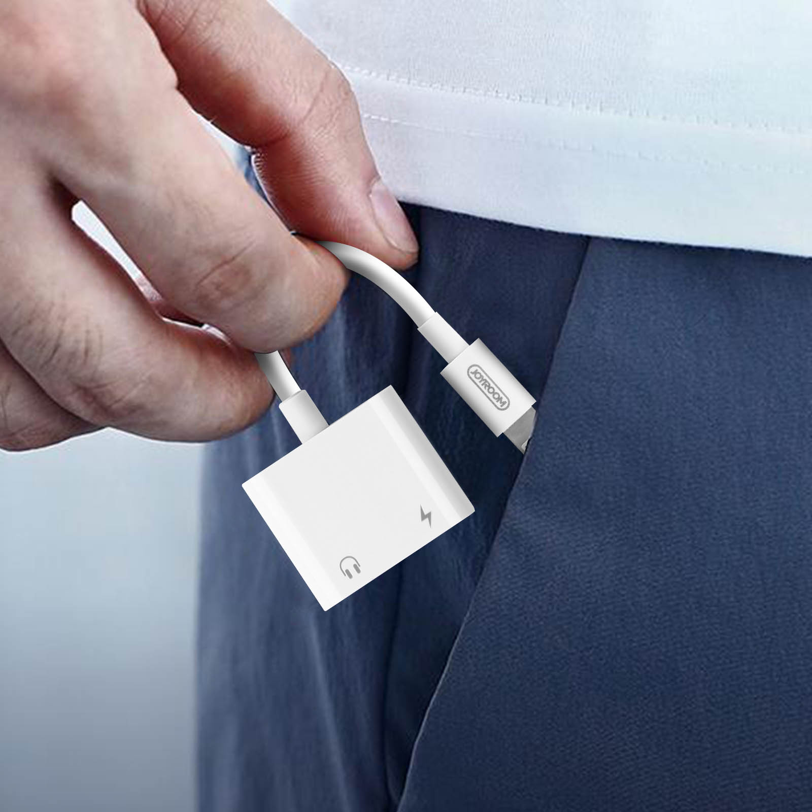 Un adaptador blanco con un cable se está insertando en un bolsillo. El adaptador está etiquetado como 'JOYROOM'.
