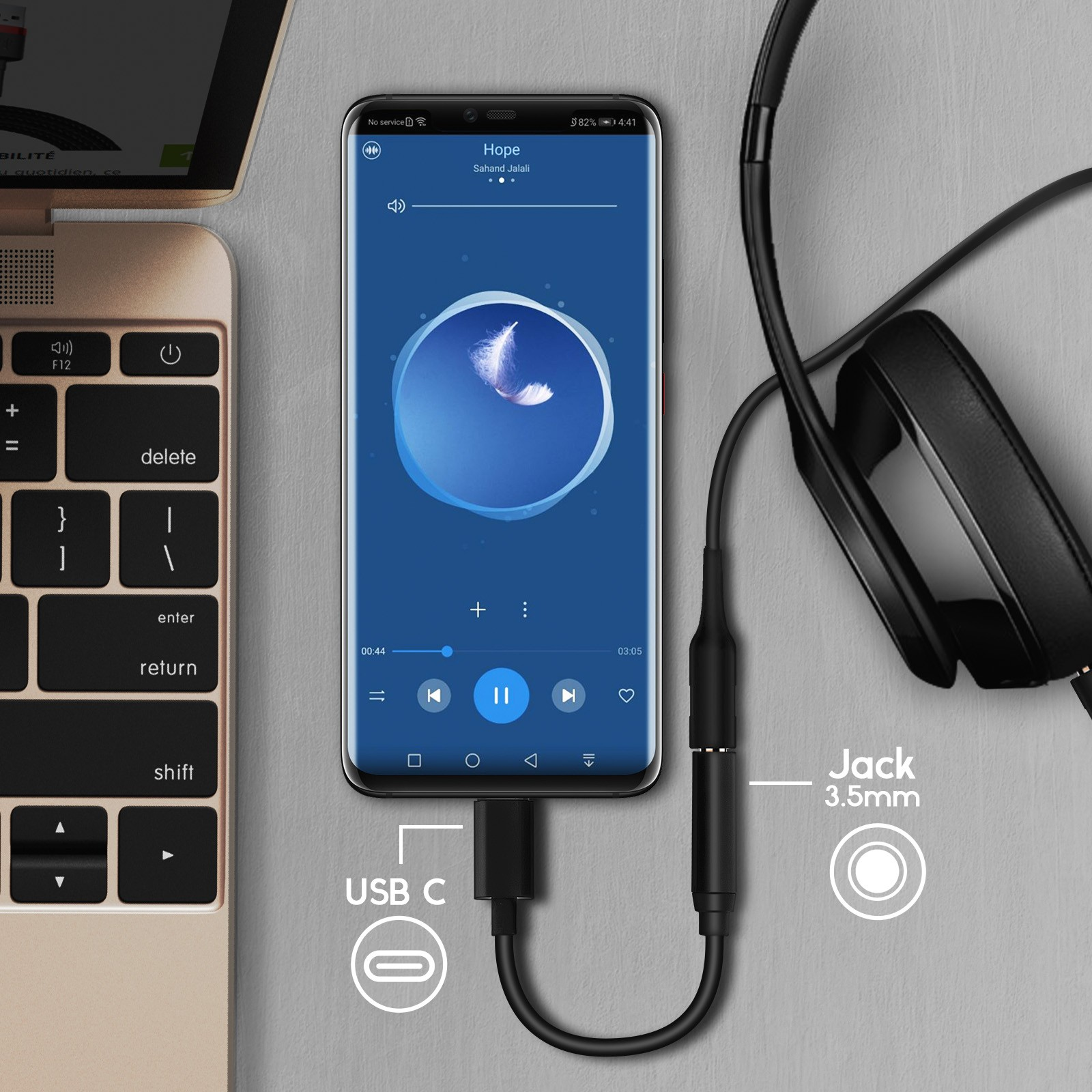 Un teléfono conectado a una computadora portátil a través de USB-C. También hay unos auriculares conectados. El teléfono muestra un reproductor de música.