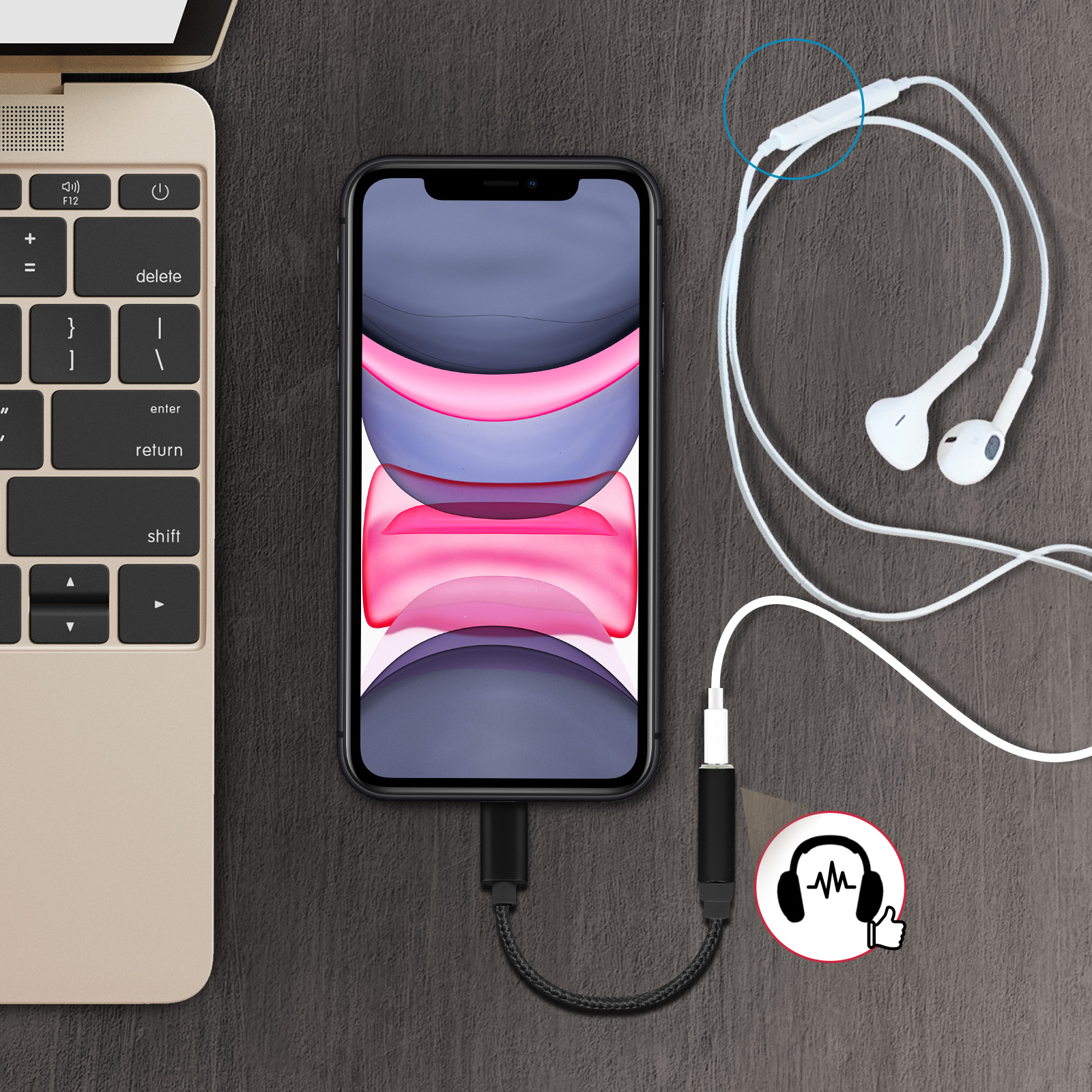 Smartphone collegato a un laptop con auricolari. Adattatore nero con icona cuffie. Tavolo di legno.
