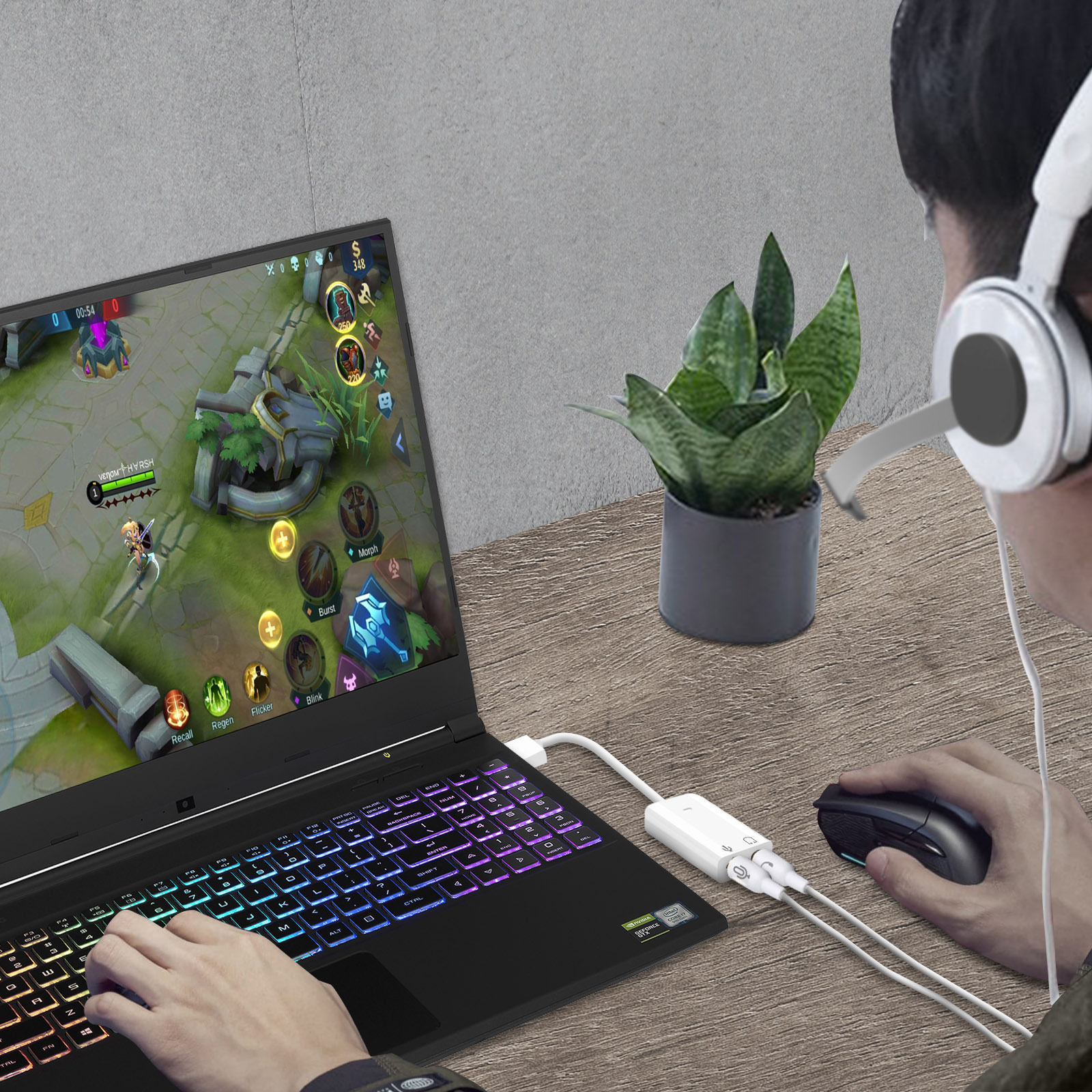 Una persona che gioca su un laptop. Sono visibili cuffie, mouse e splitter.