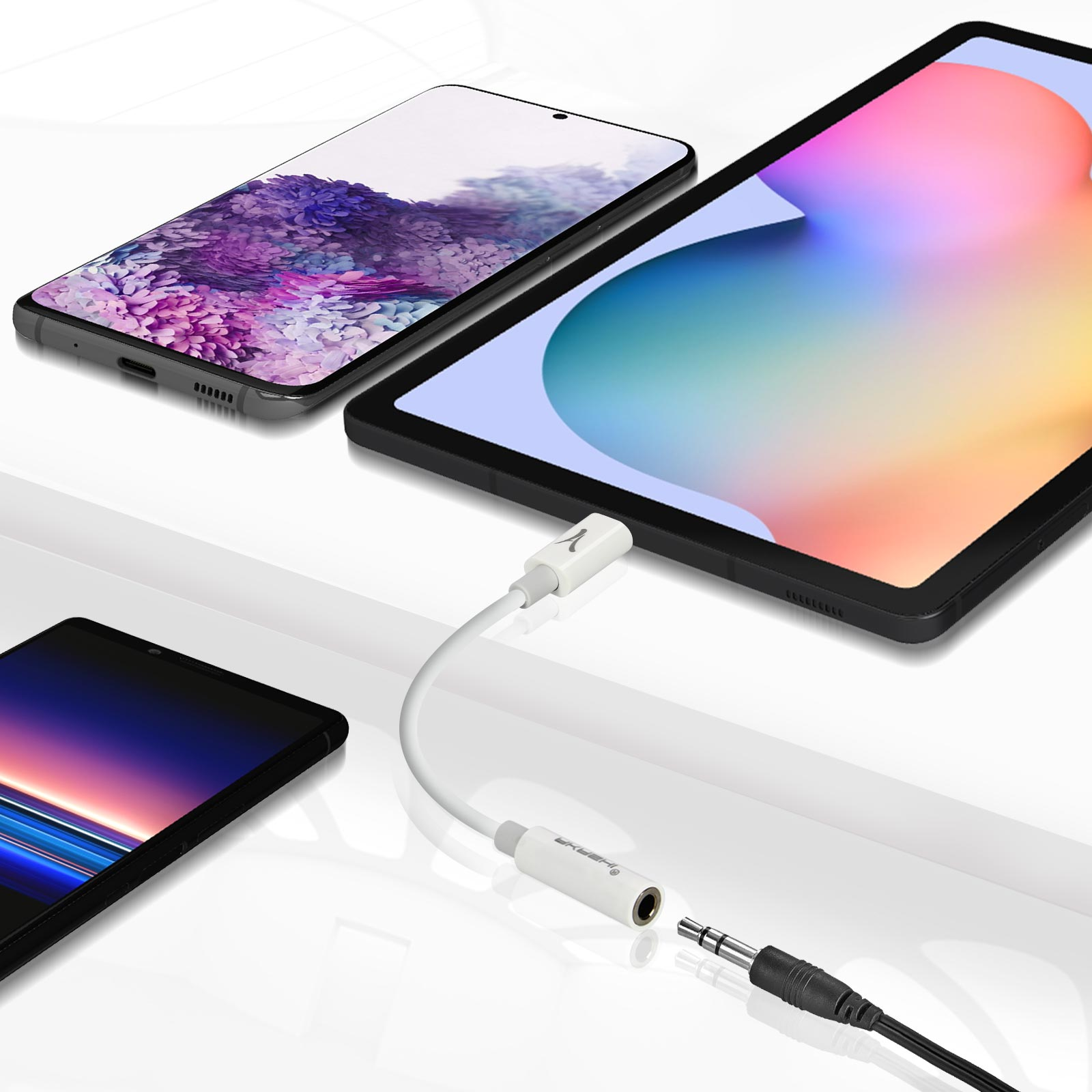 Un tablet e un telefono collegati con un adattatore audio bianco su una superficie bianca.