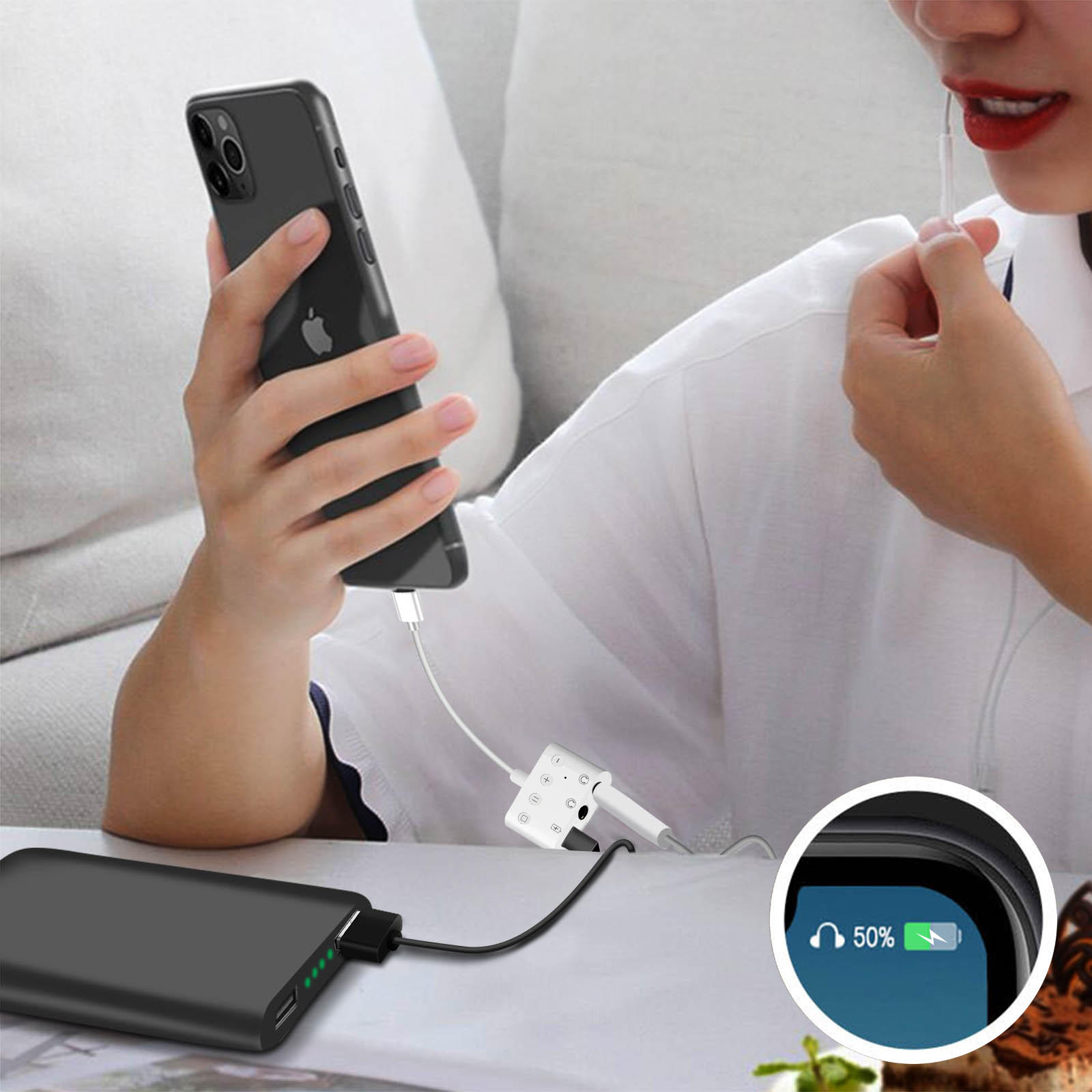 Femme utilisant un chargeur et un téléphone. Batterie affiche 50% de charge. Batterie externe et câble visibles.