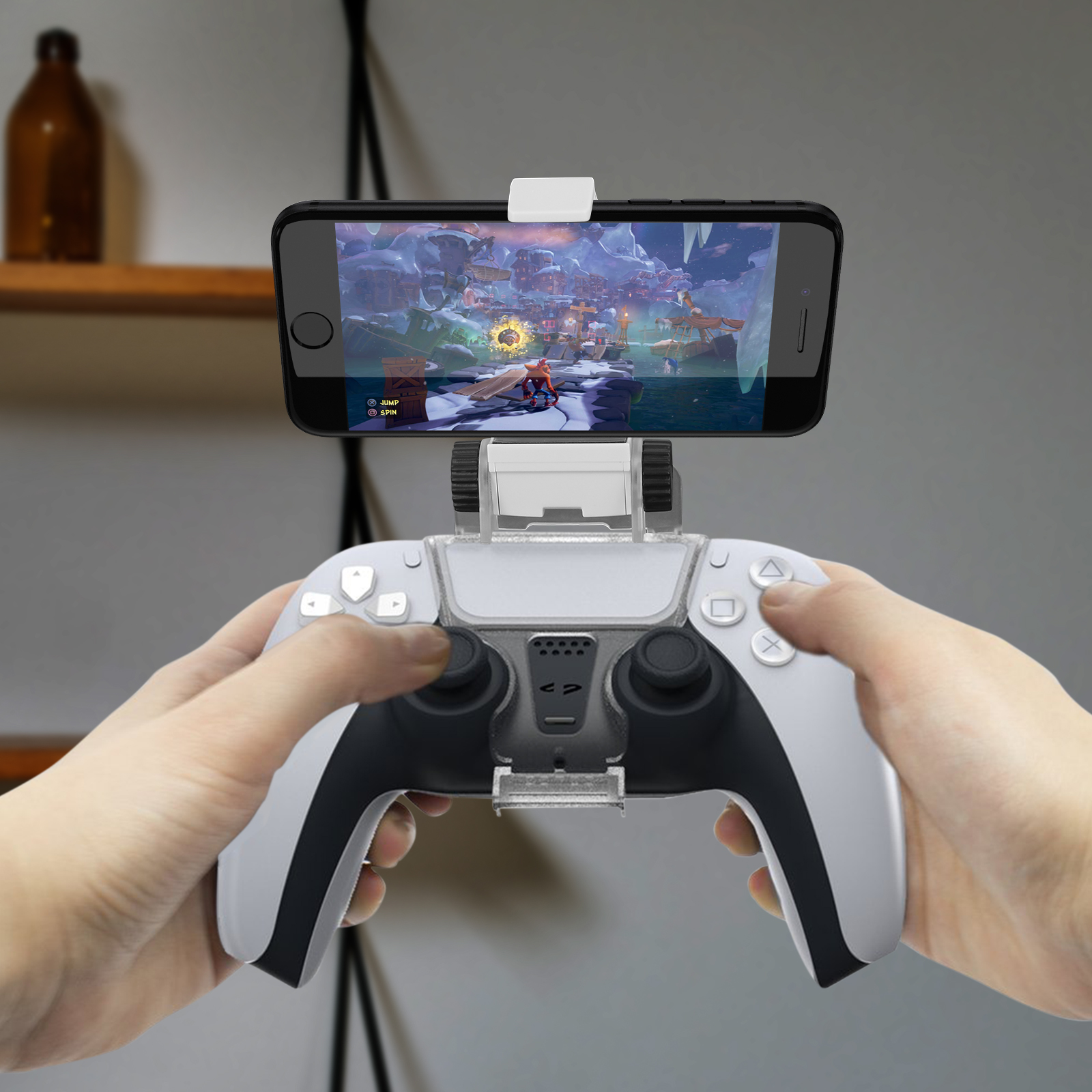 Un teléfono está montado en un controlador. El teléfono muestra un videojuego. Manos sostienen el controlador.