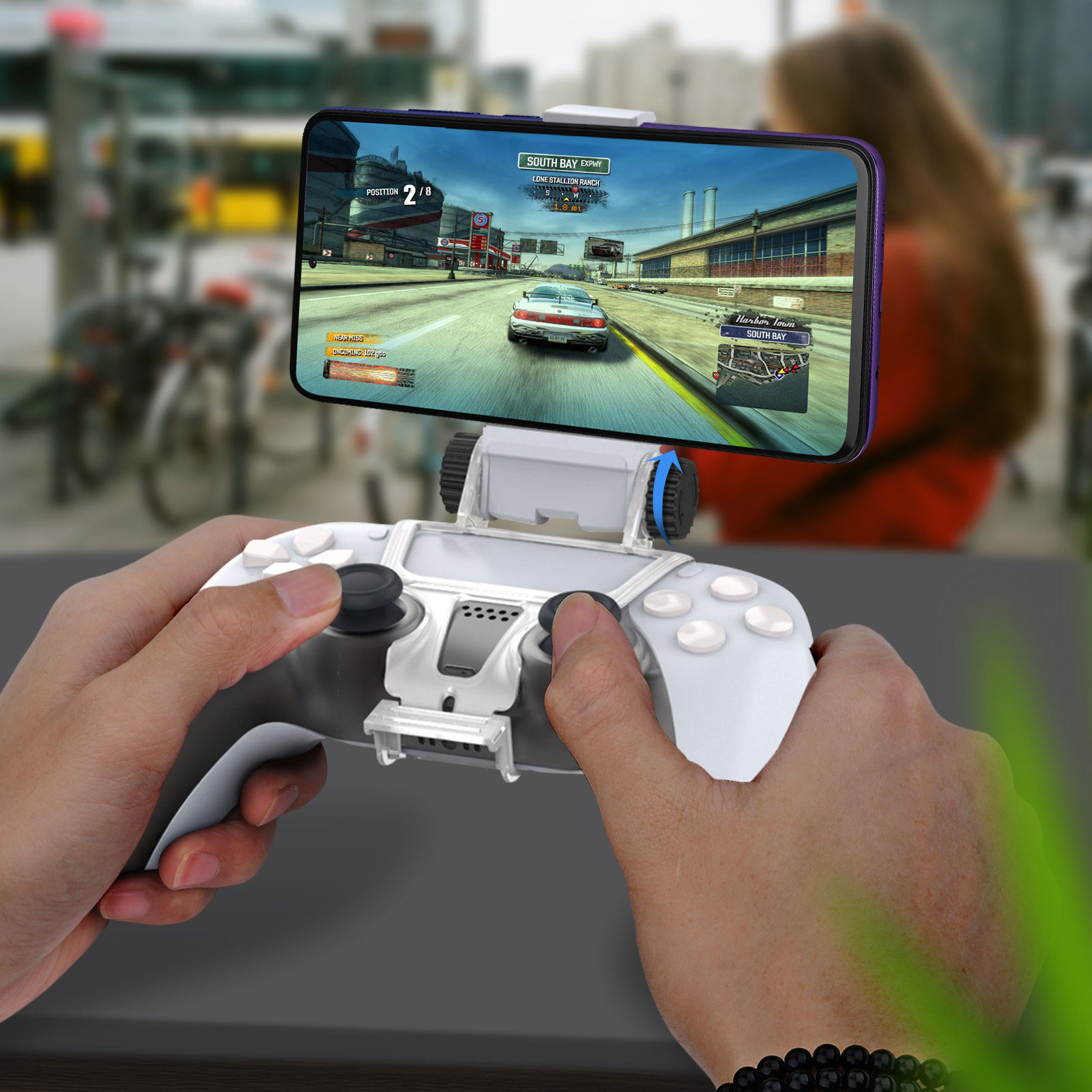 Una persona sostiene un teléfono conectado a un mando de juegos y jugando un juego de carreras.