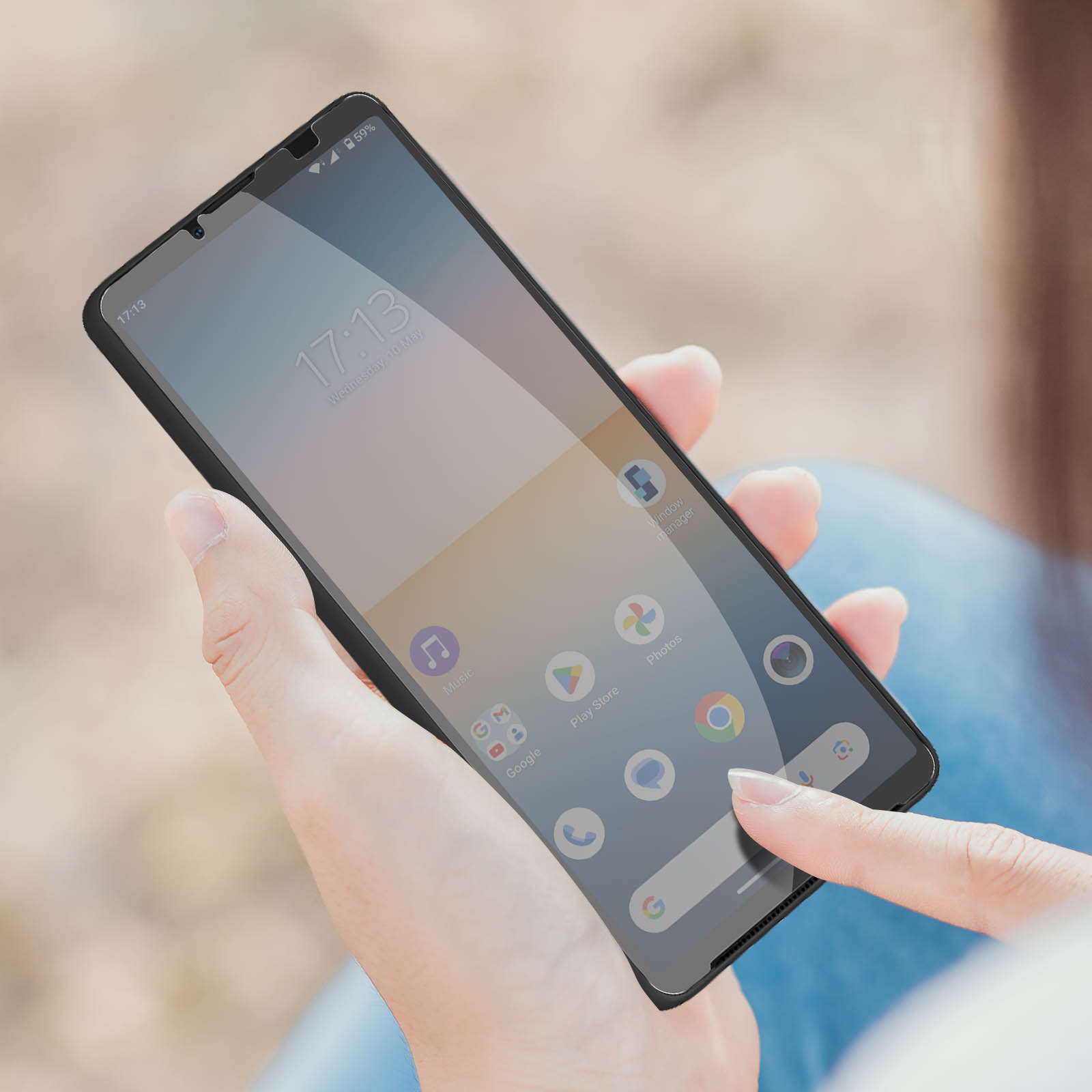 Persoon houdt een zwarte smartphone vast, vinger raakt het scherm, wazige achtergrond.