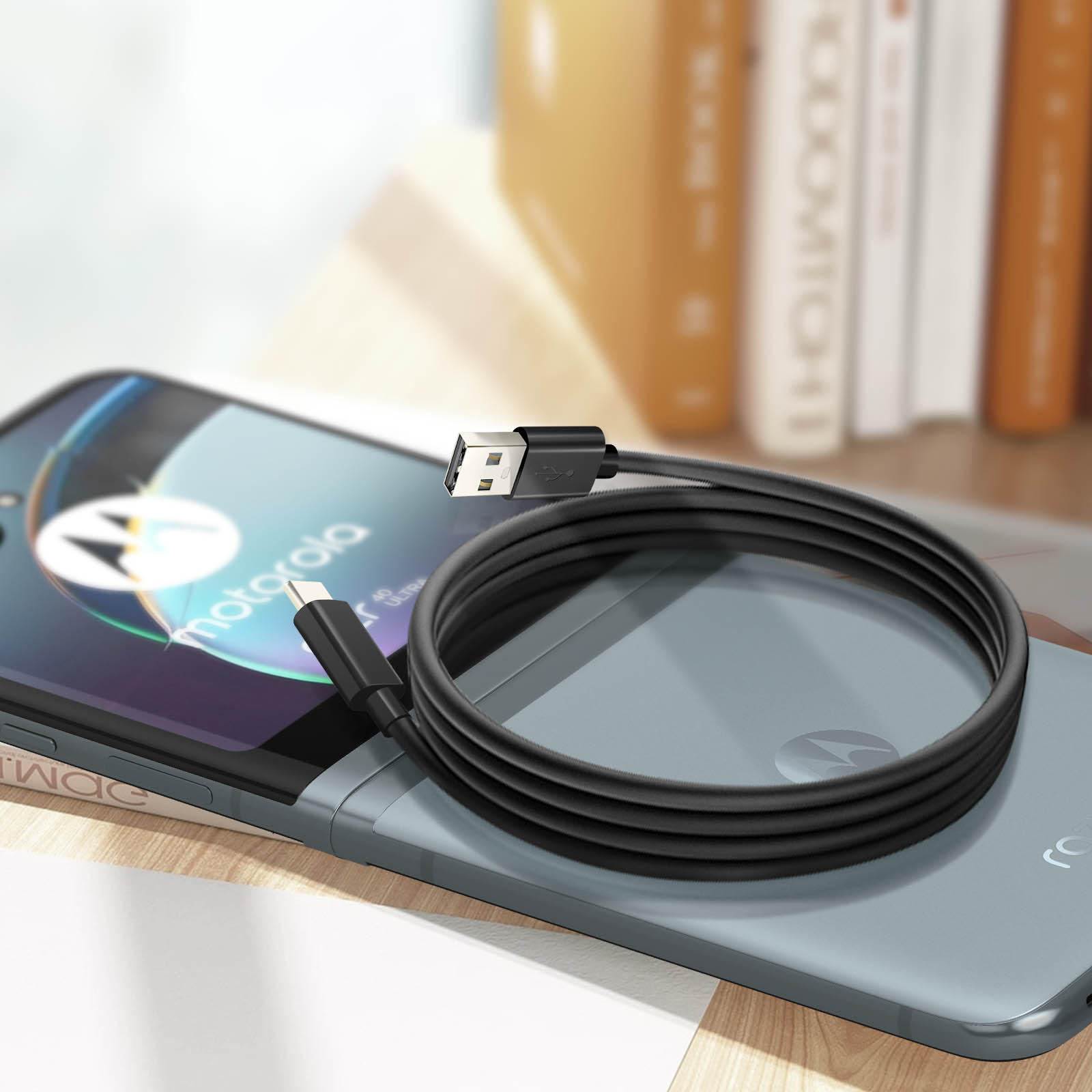 Cavo USB-C nero collegato a un telefono su una superficie di legno con libri sullo sfondo.