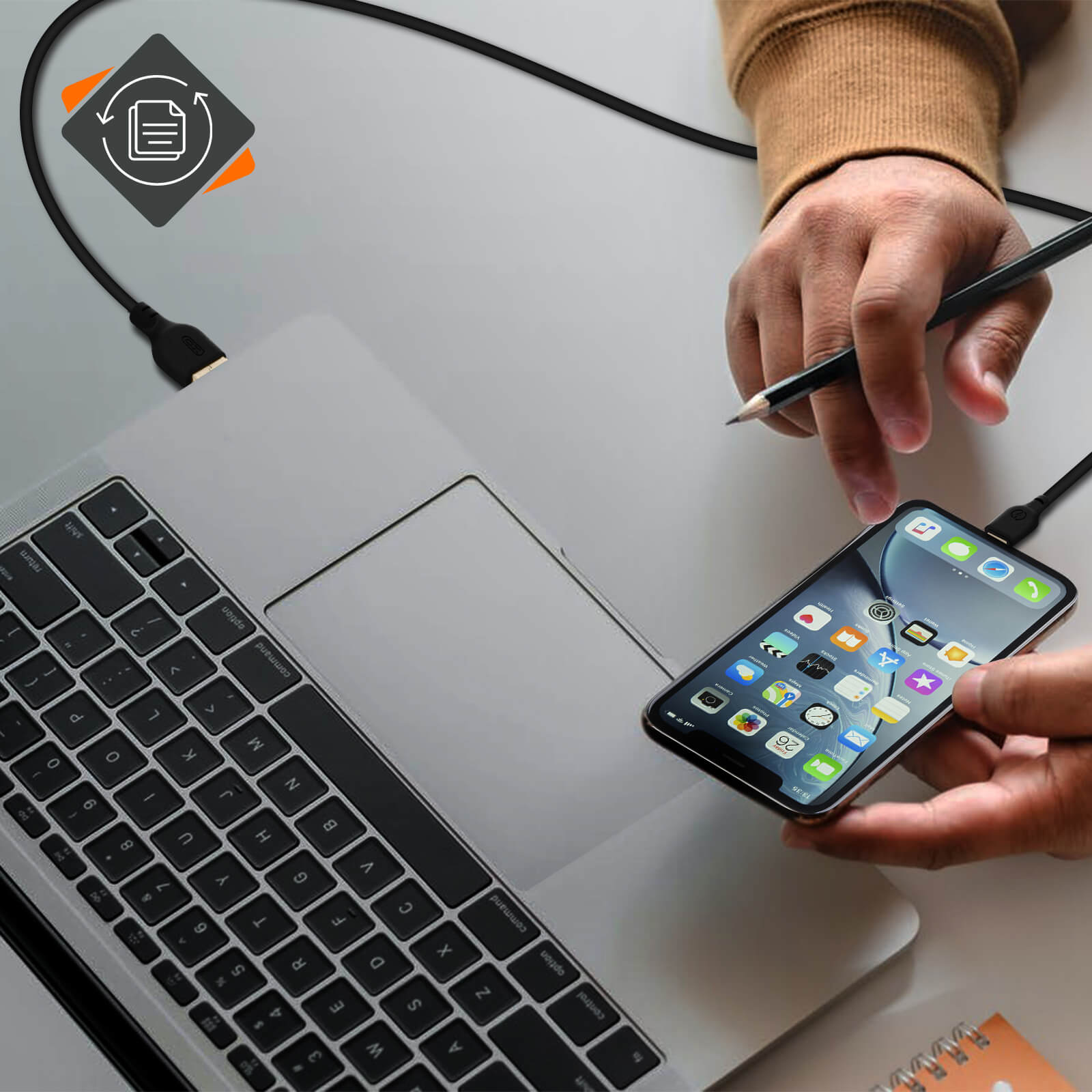Un laptop con un telefono collegato tramite un cavo nero; una matita è tenuta vicino al telefono.