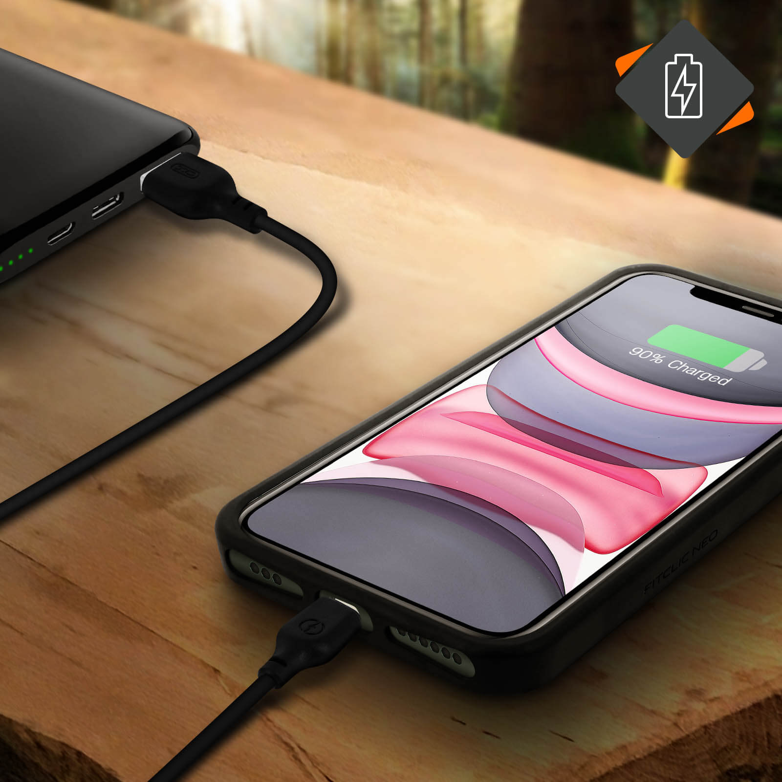 Telefono in carica su tavolo di legno con power bank. Il telefono mostra 90% di carica.