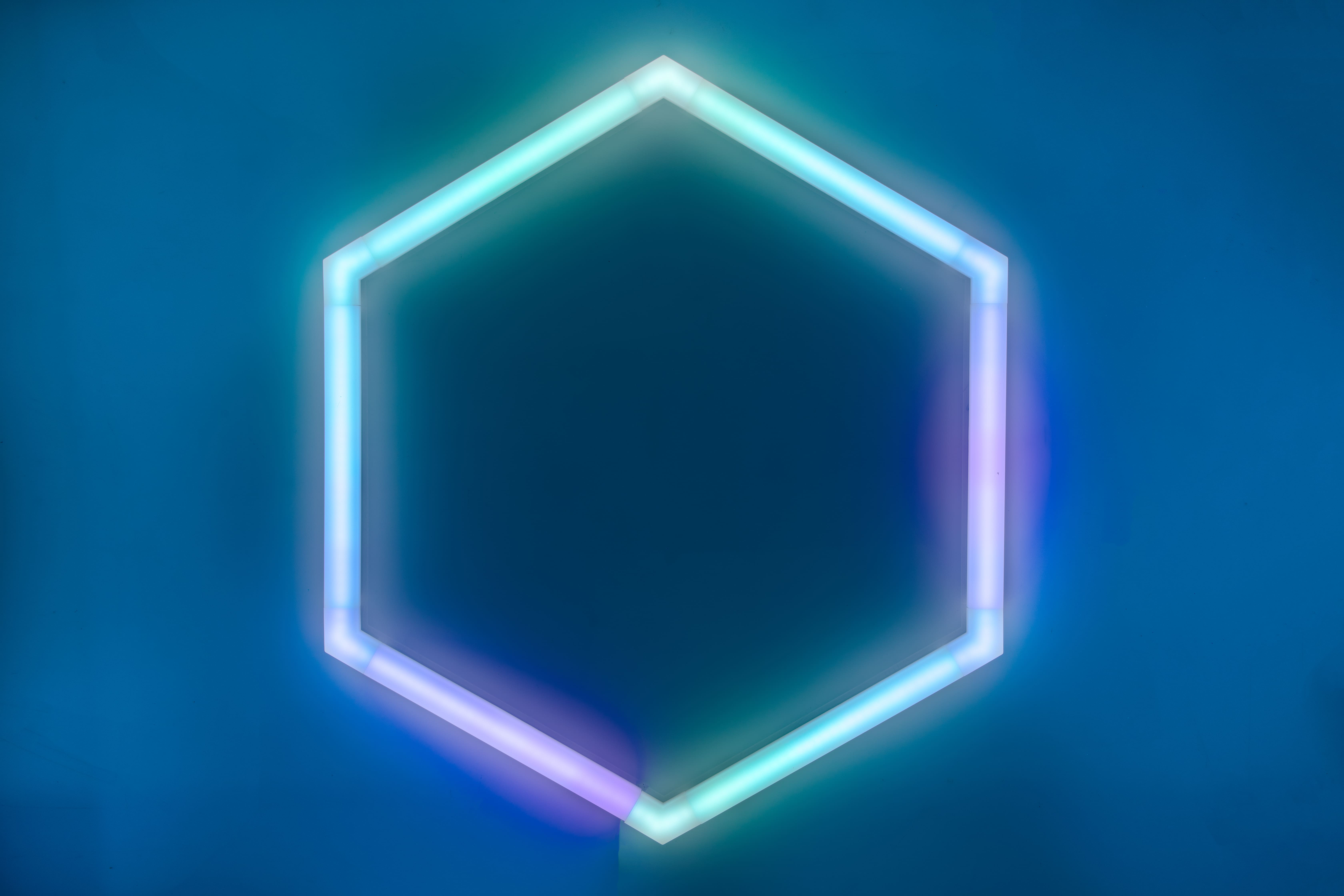 Sechseckform mit Neonumriss auf dunkelblauem Hintergrund.