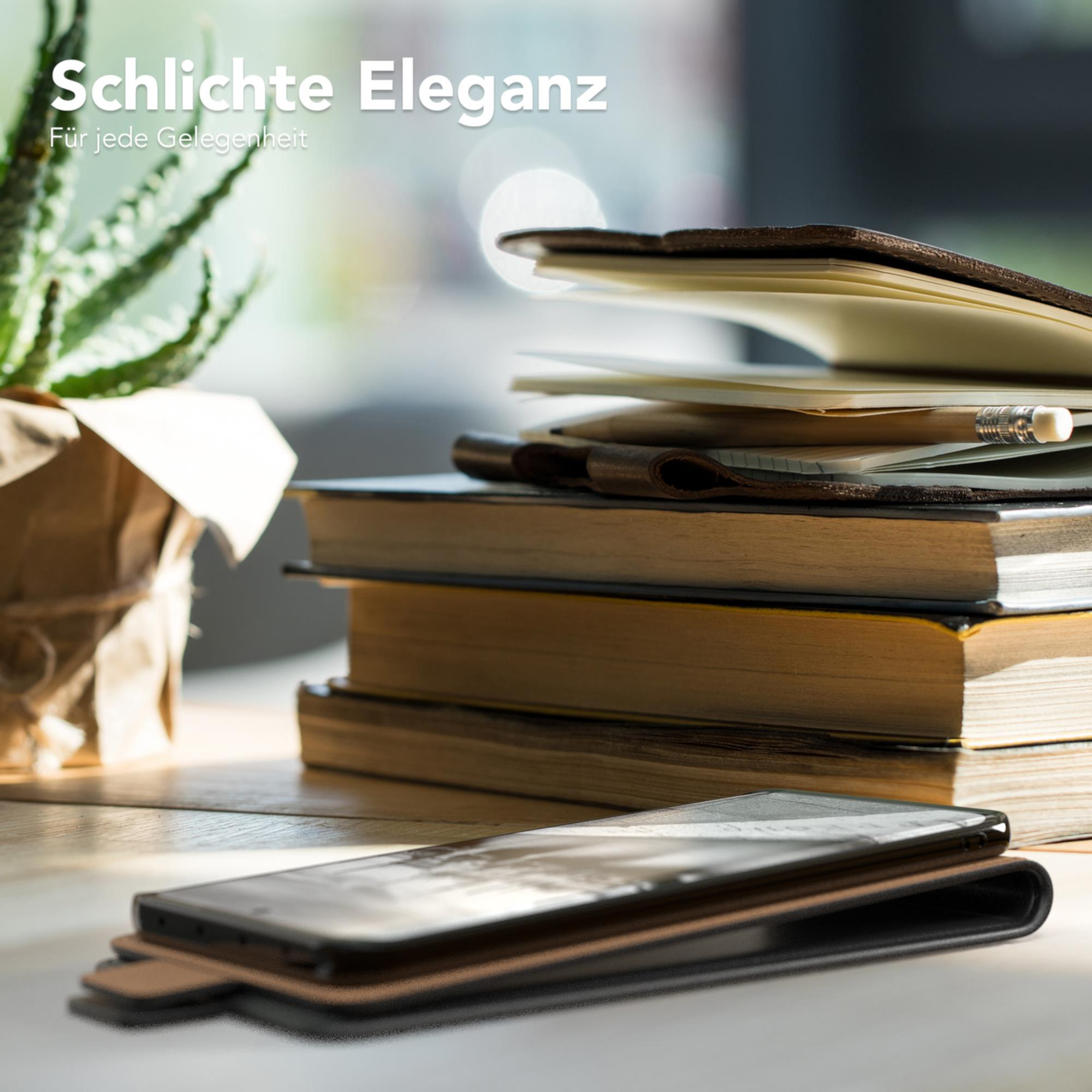 Ein Stapel Bücher und ein Telefon in einer Hülle auf einem Holztisch, mit einer Pflanze im Hintergrund.