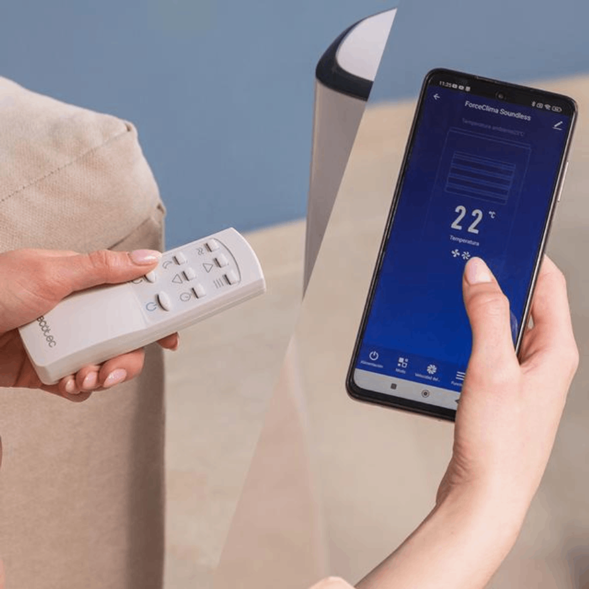 Kobieta trzyma pilota i telefon. Telefon wyświetla interfejs aplikacji.