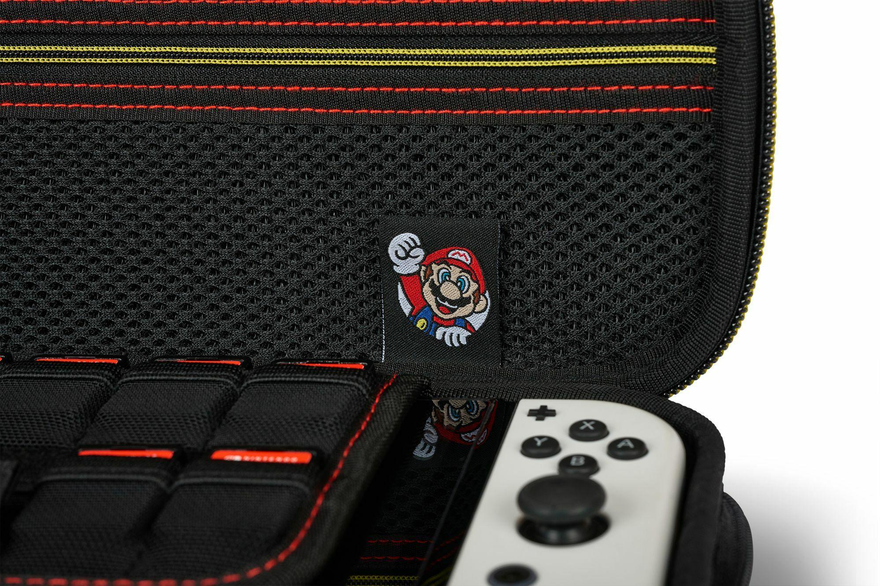 Dentro de una funda de transporte Nintendo Switch negra y roja, con un parche de Mario y un mando blanco.