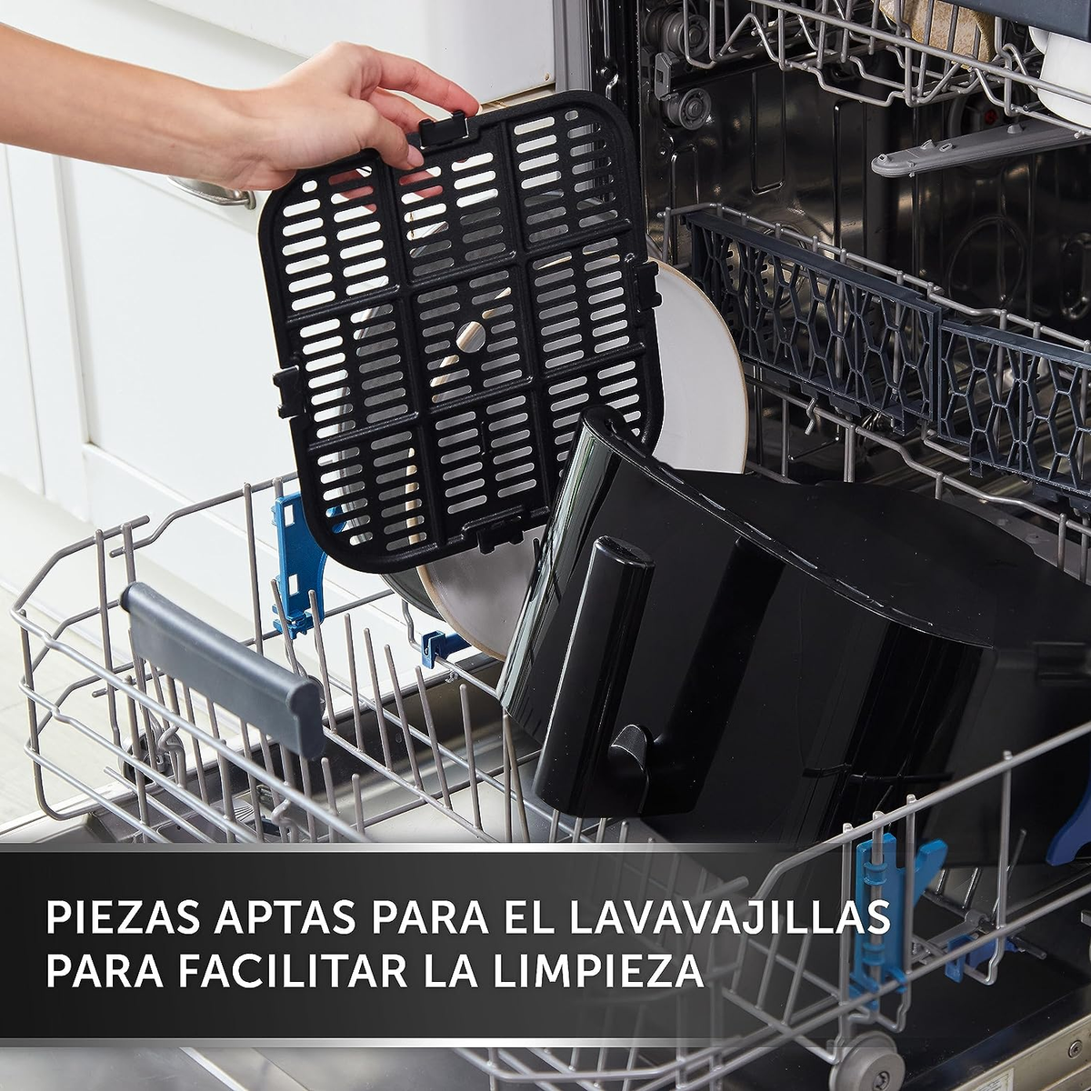 Lavavajillas con piezas cargándose. Piezas negras de freidora de aire y un plato blanco.