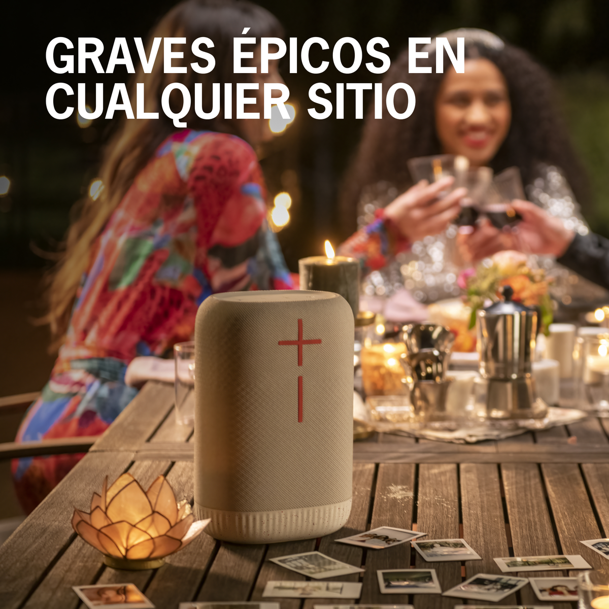 Głośnik na stole z ludźmi w tle. To beżowy walec z czerwonym krzyżem.