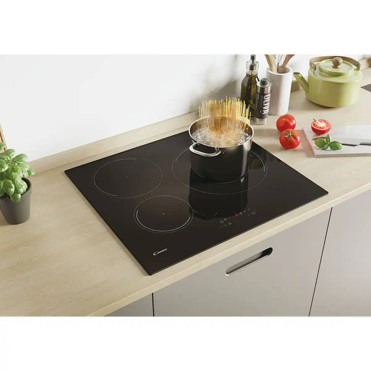 Blat kuchenny z czarną płytą indukcyjną. Garnek ze spaghetti stoi na jednym palniku.