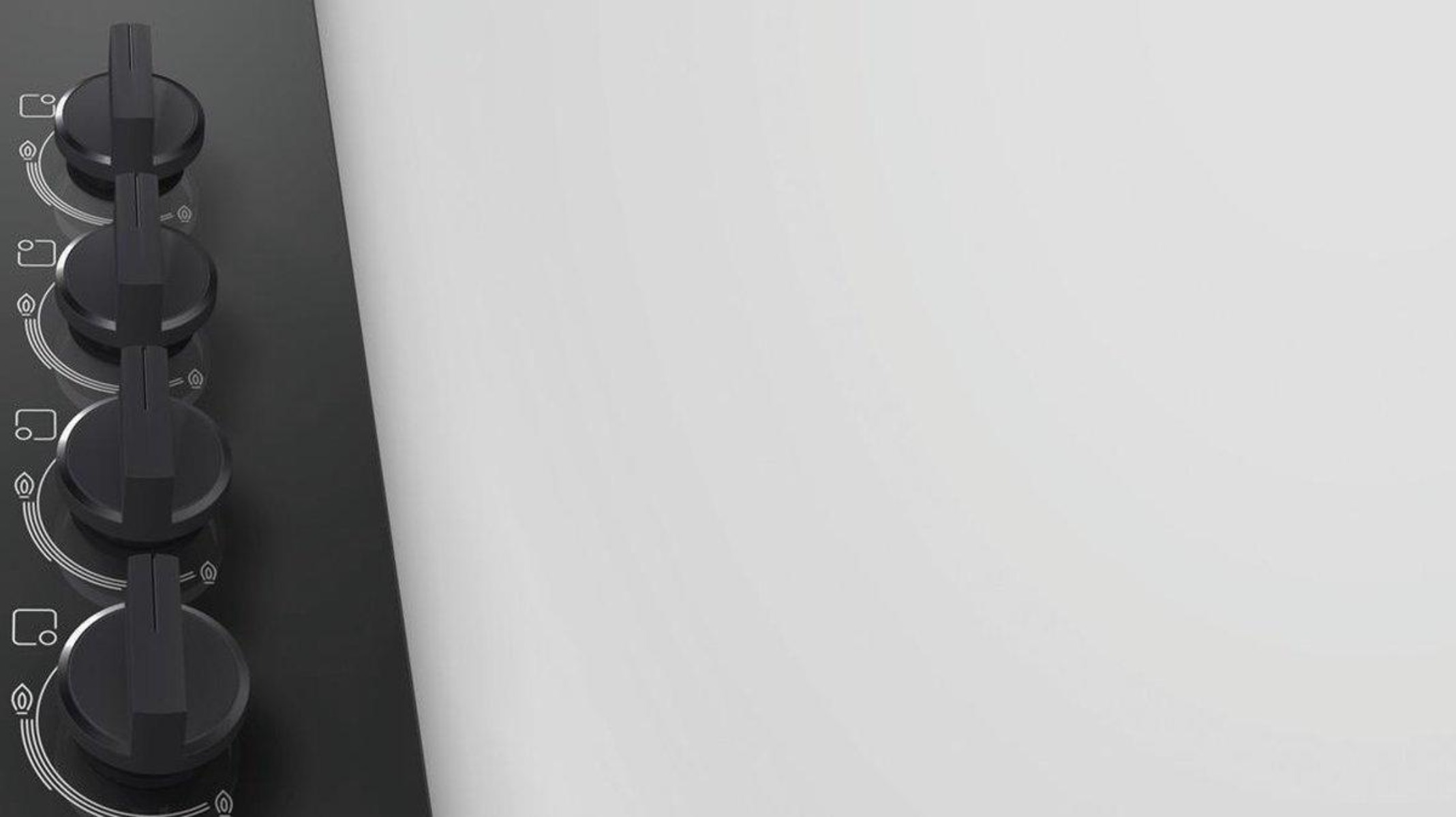 Piano cottura nero con quattro manopole, posto sul lato sinistro, con sfondo bianco.
