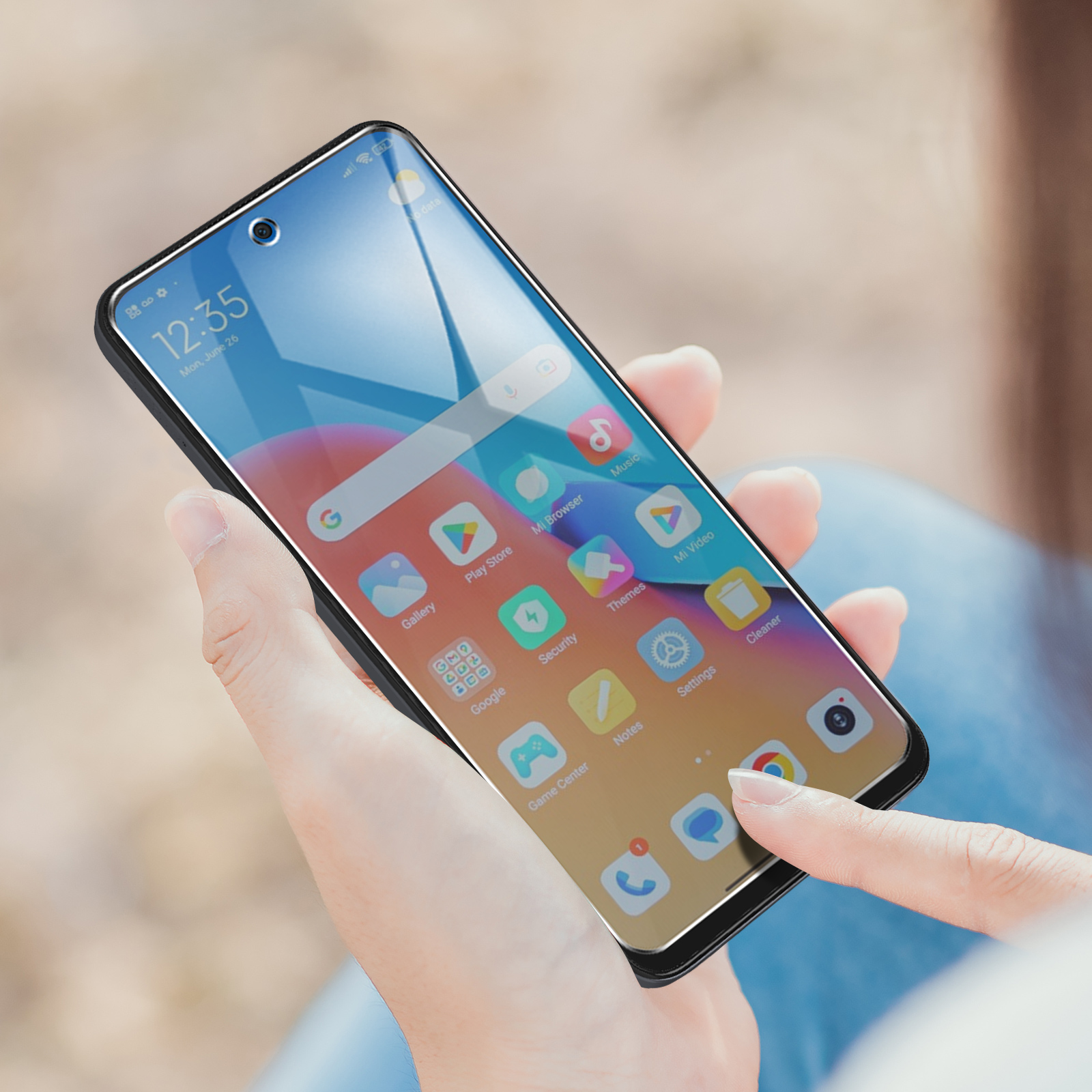 La mano di una persona tocca lo schermo di un telefono con icone, mostrando l'ora e uno sfondo sfocato.