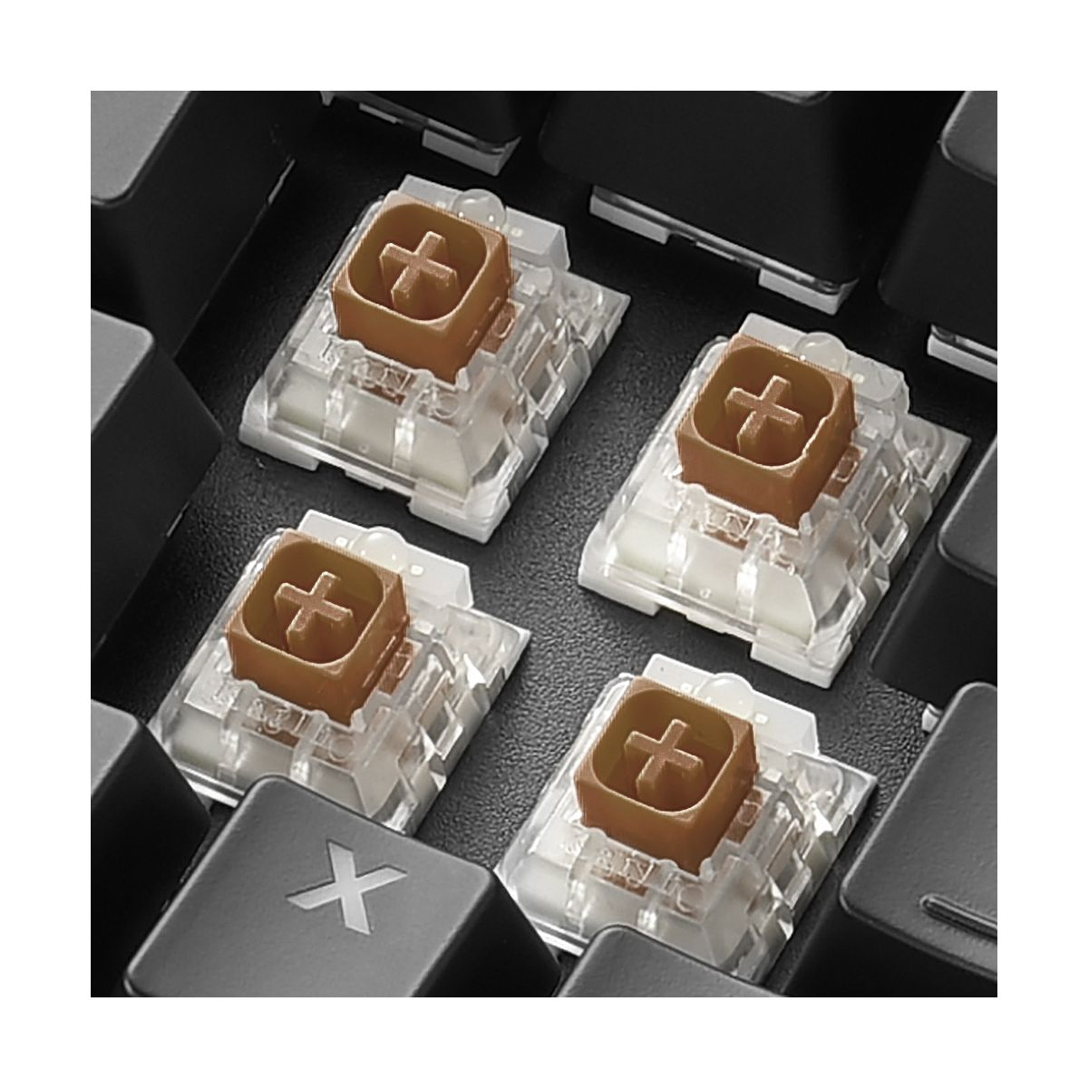 Zbliżenie na cztery brązowe przełączniki klawiatury na czarnym tle, pokazujące trzpienie w kształcie krzyża.