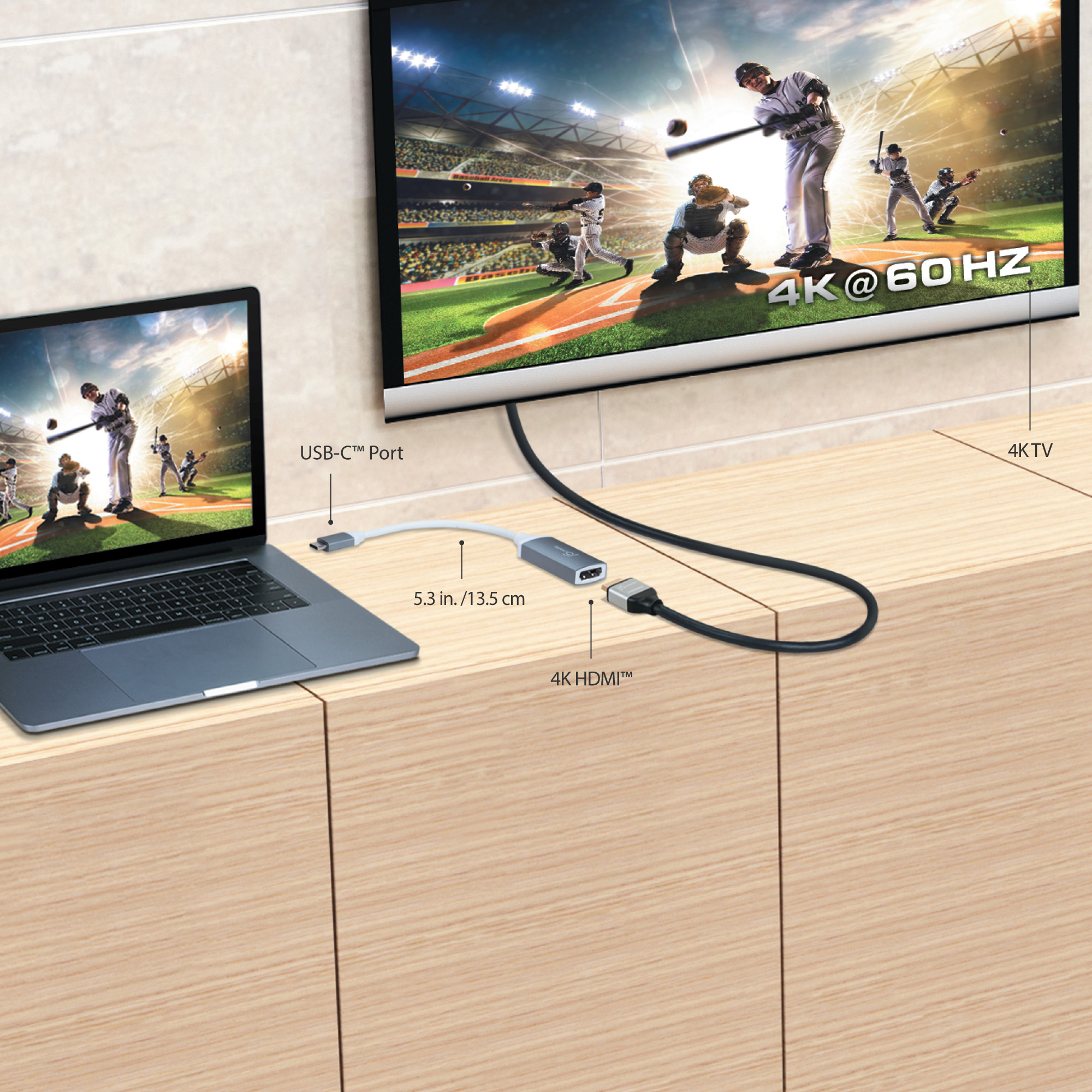 Un portátil conectado a un televisor con un cable. Un partido de béisbol está en la pantalla del televisor.