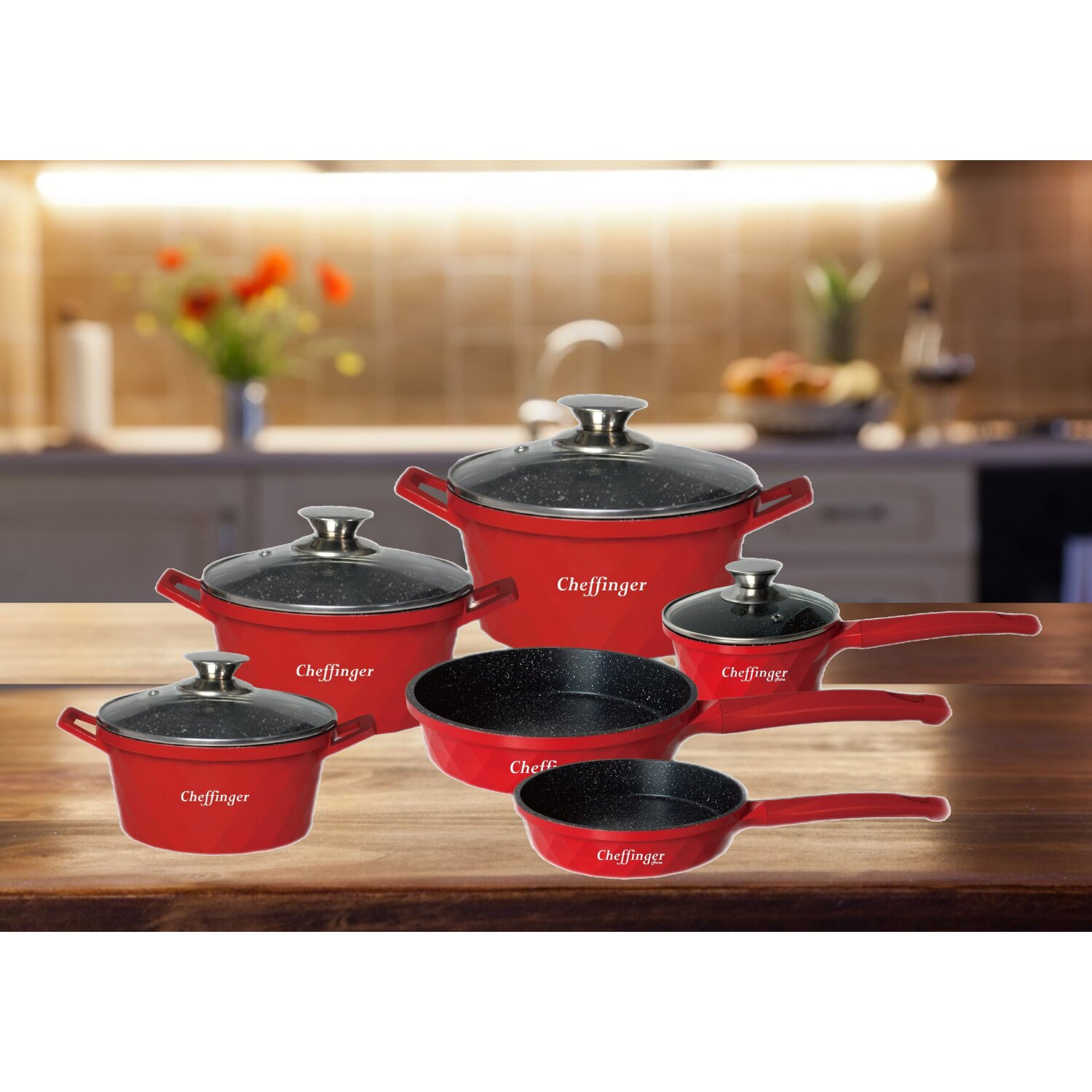 Rotes Kochgeschirr-Set mit schwarzen, gesprenkelten Innenräumen auf einem Holztisch.