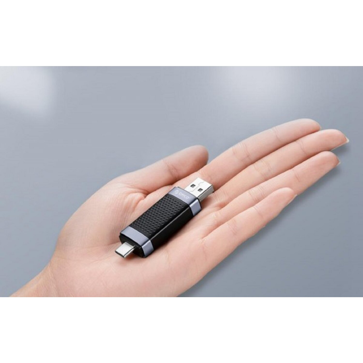 Una chiavetta USB nera e argento tenuta in mano da una persona. La chiavetta USB ha un connettore USB-A e USB-C.