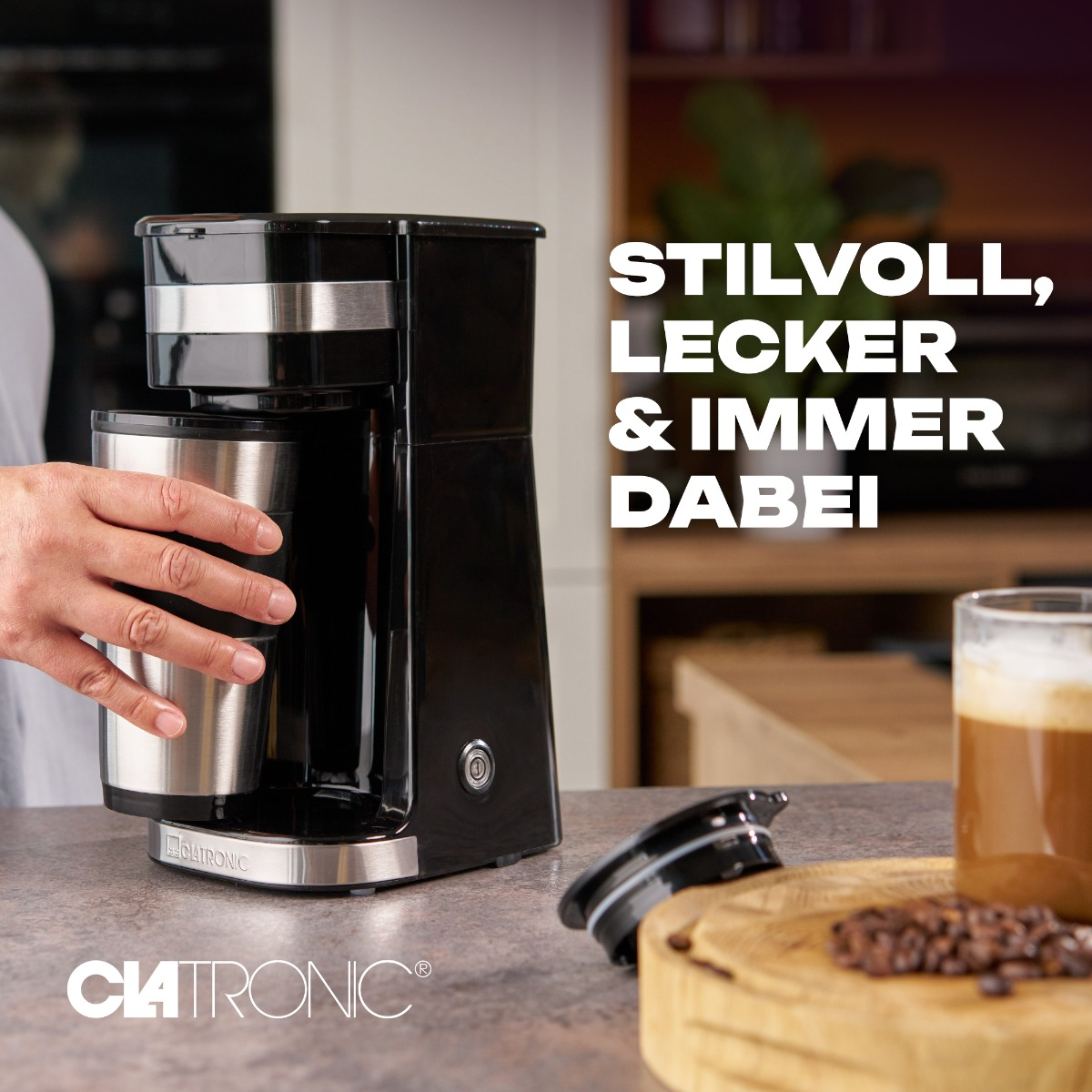 Czarny ekspres do kawy ze srebrnym pojemnikiem i tekstem na blacie ze szklanką.