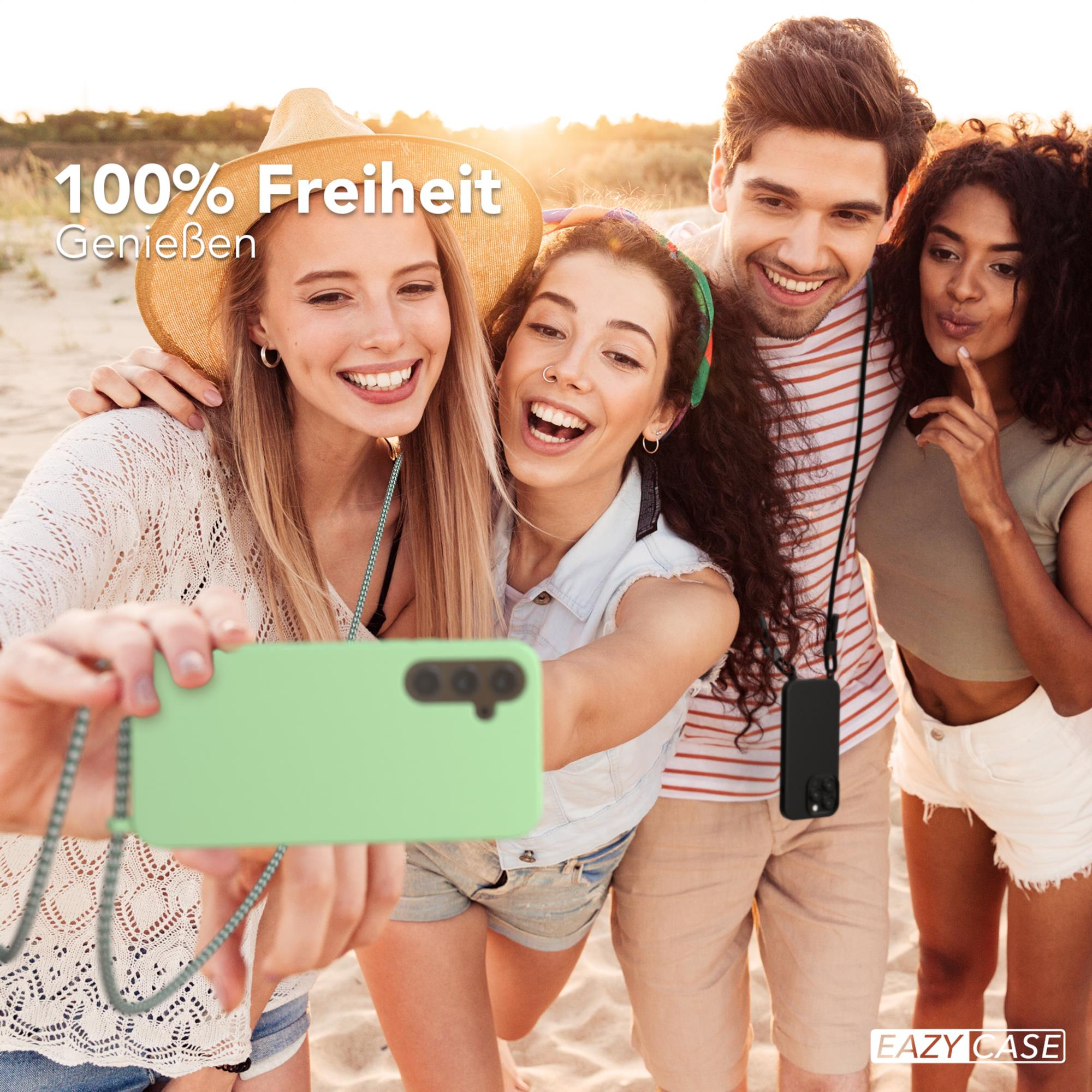 Vier Personen machen ein Selfie am Strand. Einer hält ein grünes Telefon an einer Schnur.
