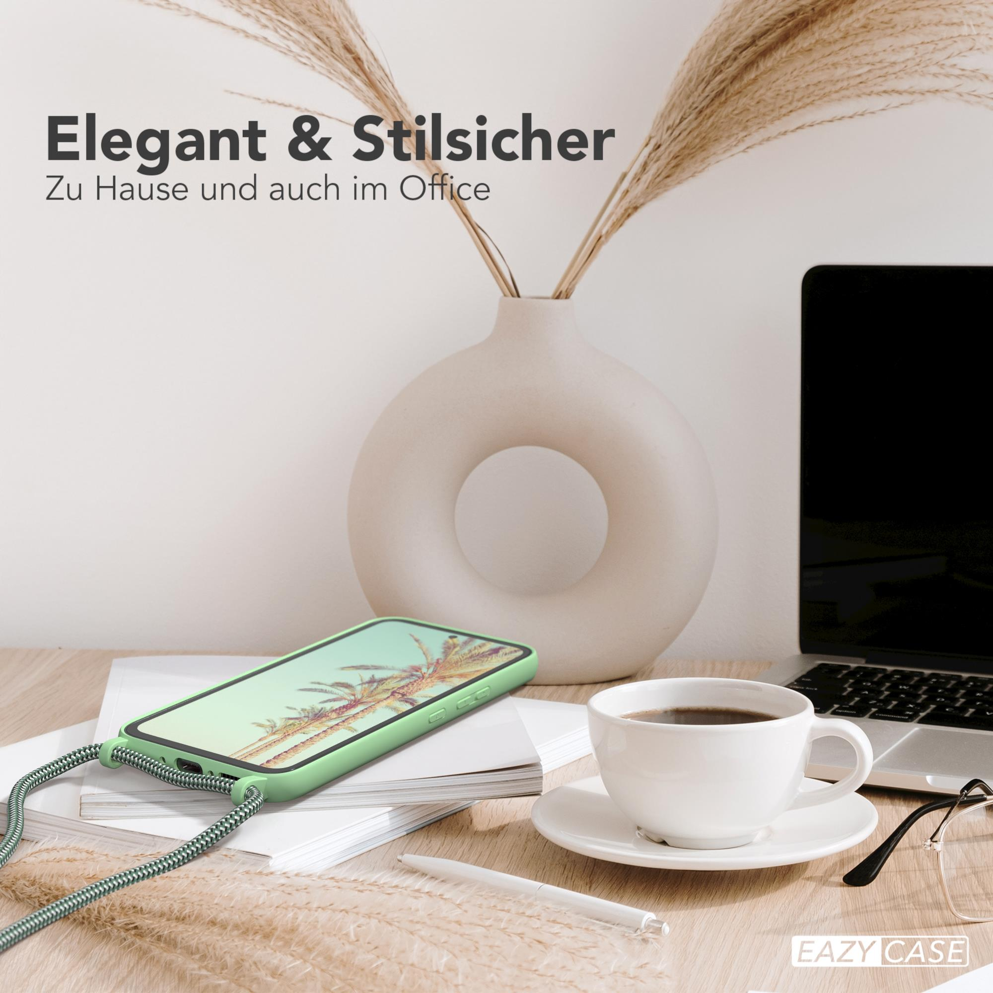 Ein Telefon in einer grünen Hülle mit geflochtenem Riemen auf einem Schreibtisch, mit Kaffeetasse und Laptop.