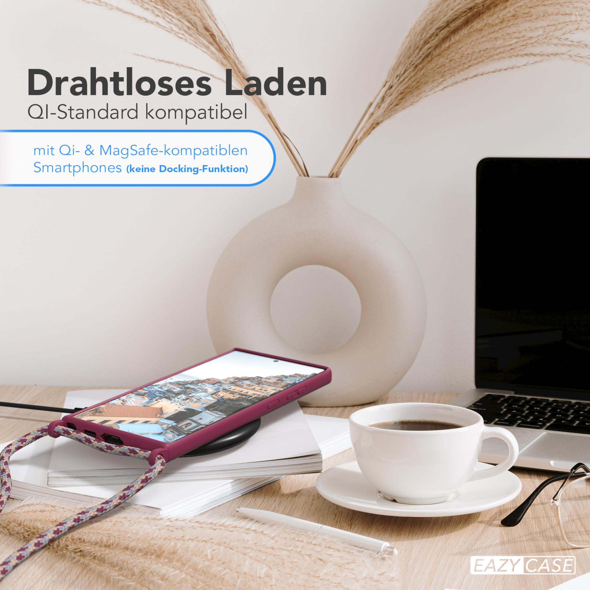 Telefon in einer Hülle auf einem Schreibtisch mit Kaffee und einer Vase. Text: 'Kabelloses Laden'.