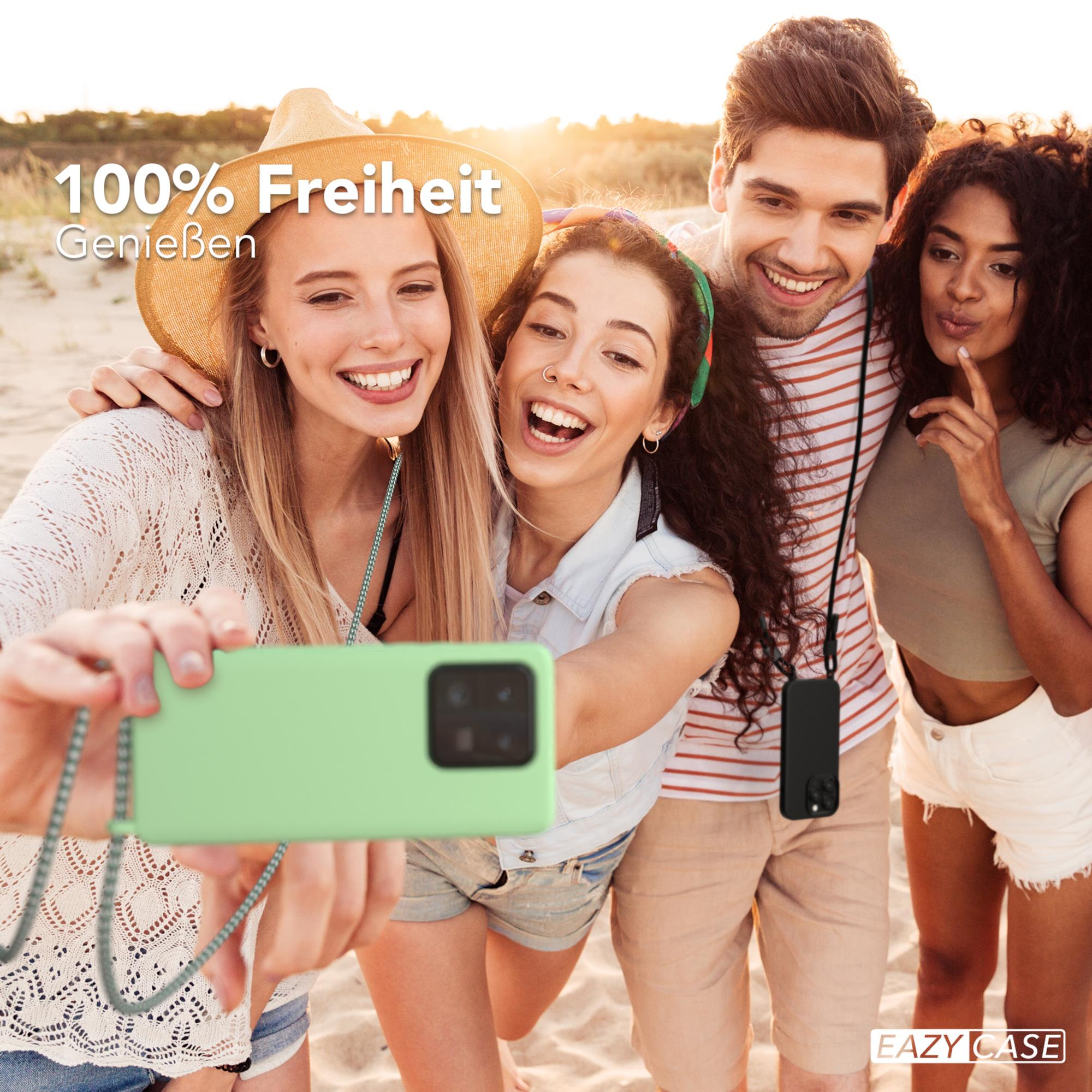 Vier Freunde machen ein Selfie am Strand, einer hält ein grünes Telefon.
