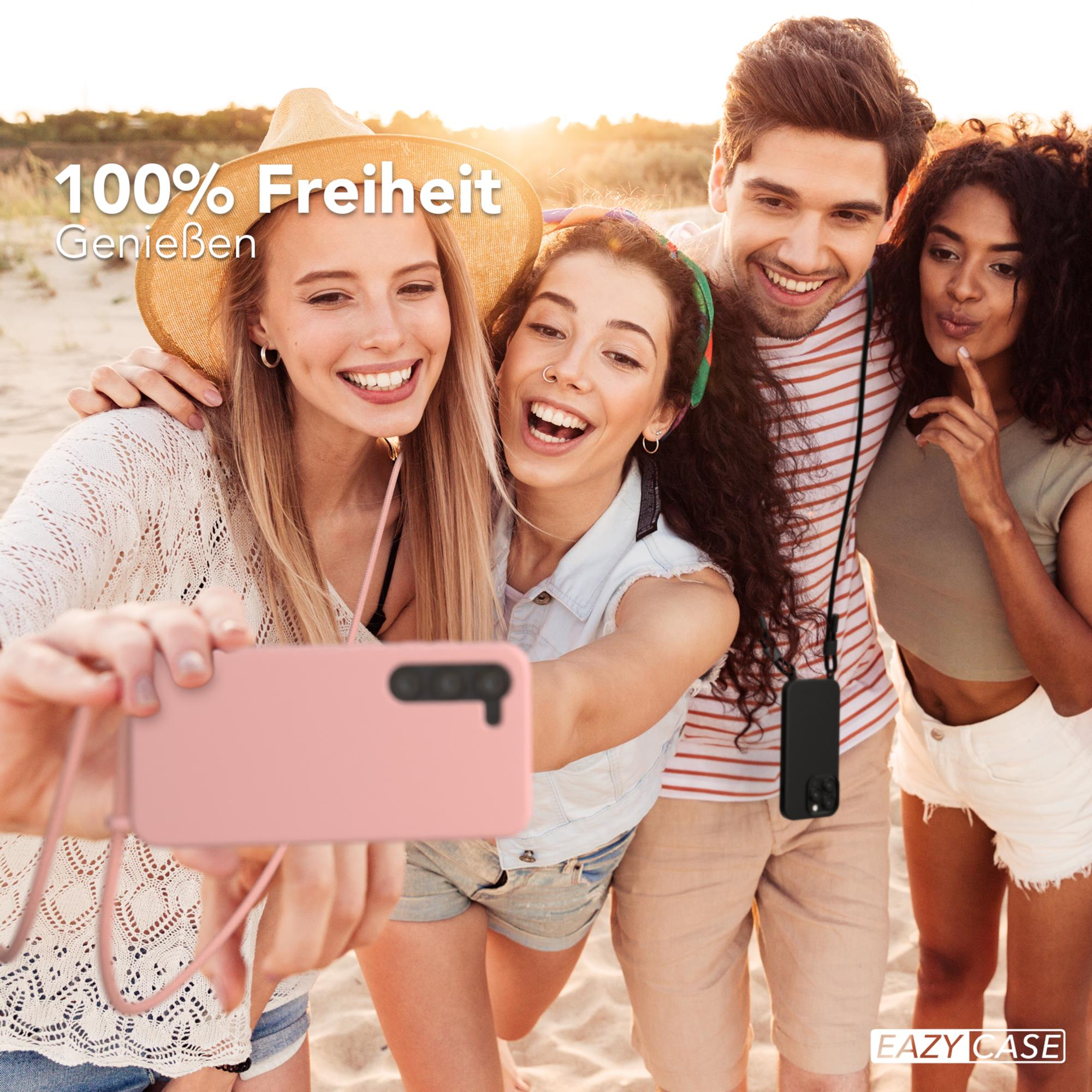 Freundesgruppe macht Selfie am Strand, hält eine pinke Handyhülle.