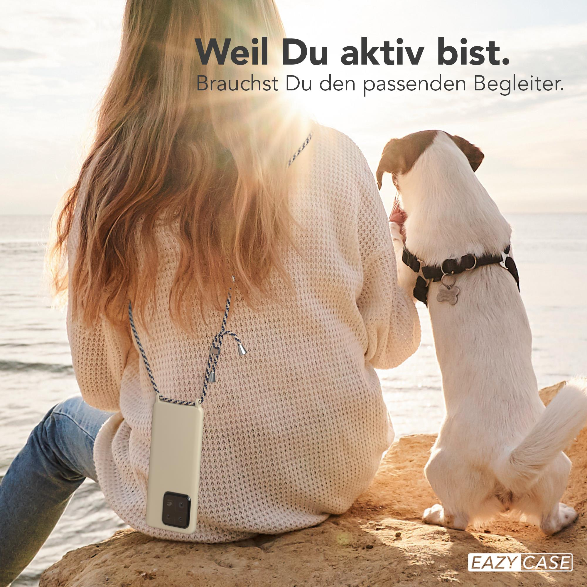Eine Frau sitzt mit einer Handyhülle, während ein Hund sie ansieht. Sie sind in der Nähe des Wassers.