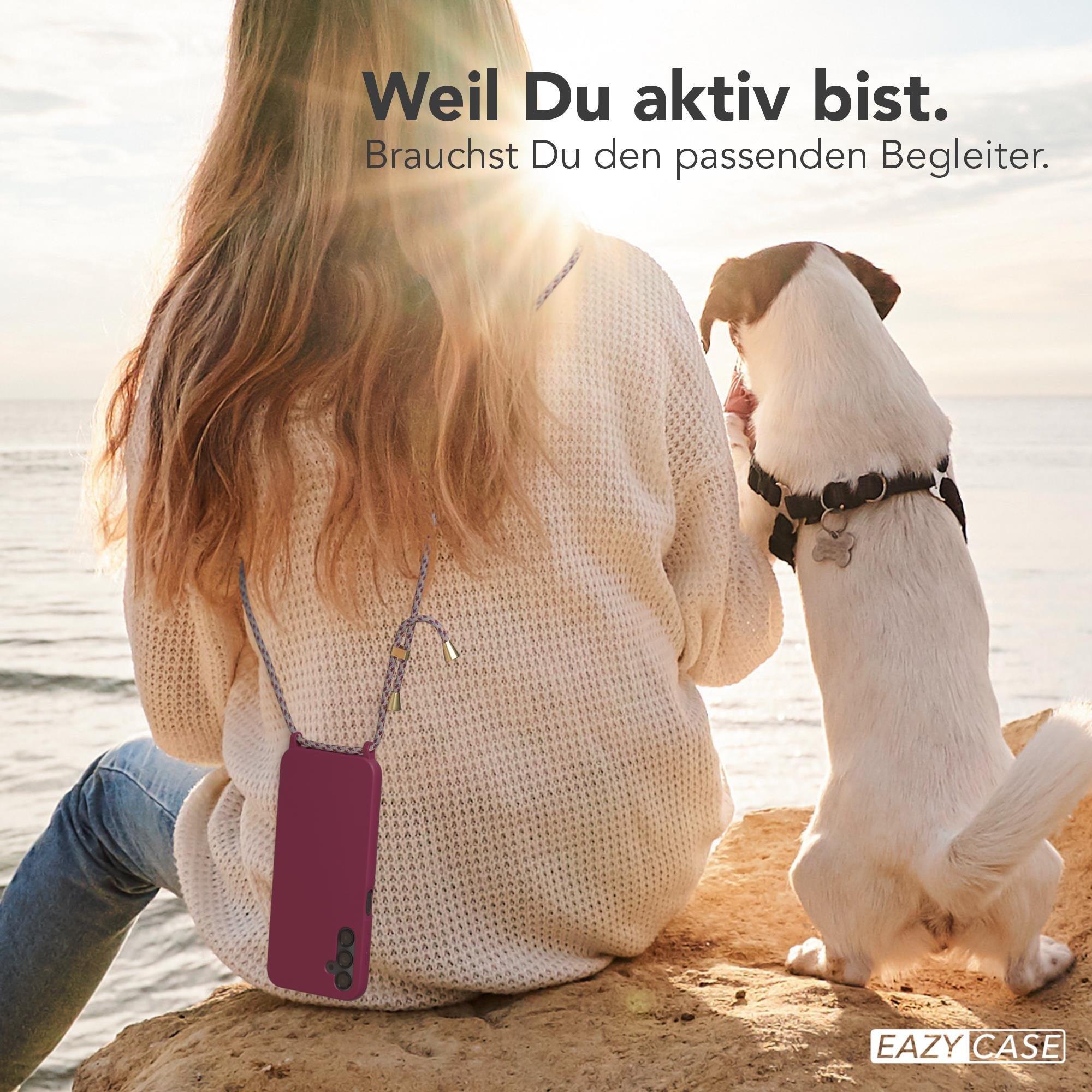 Eine Frau mit einem Hund am Meer, beide mit Handyhüllen.
