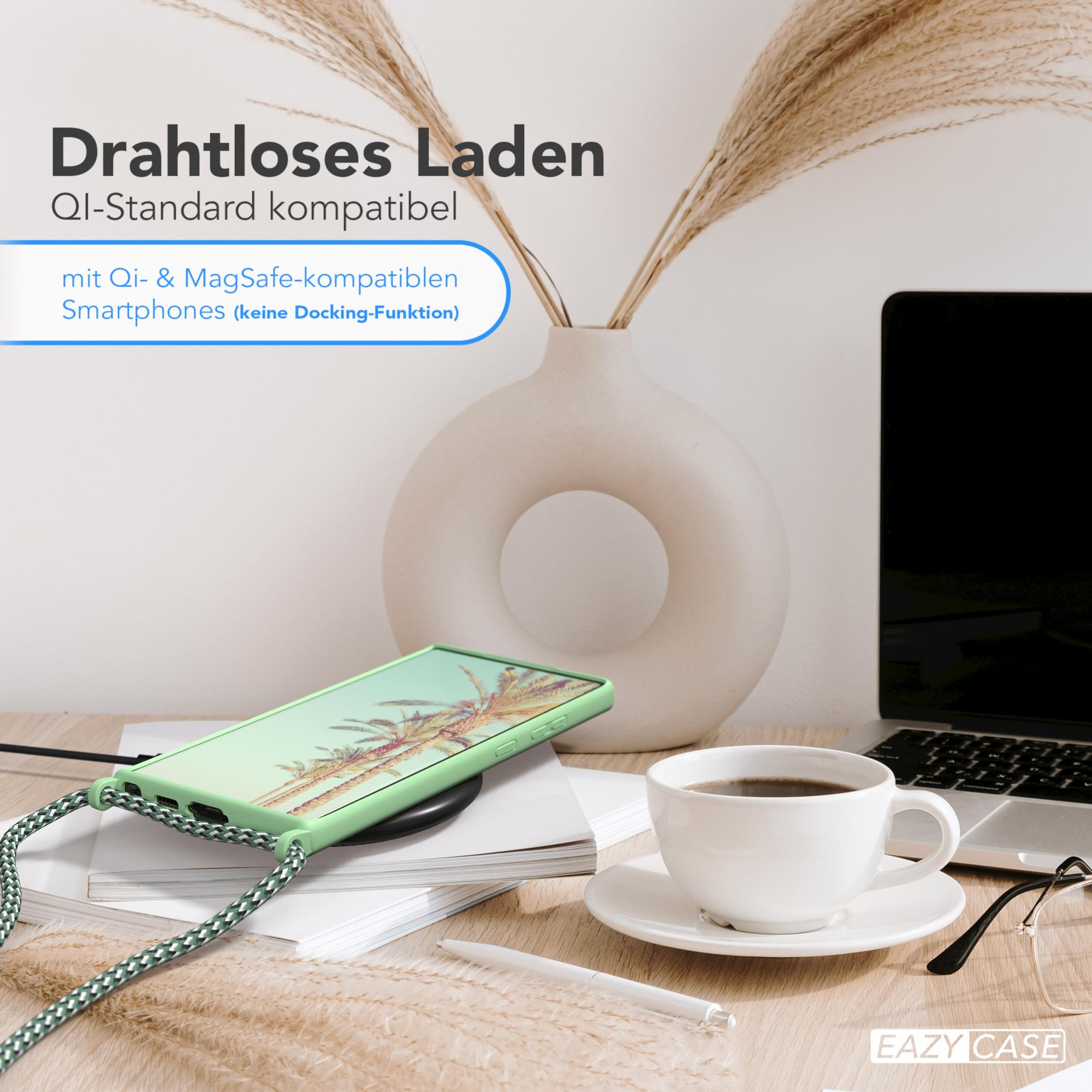 Telefon auf kabellosem Ladegerät neben einer Tasse Kaffee und Vase mit Pflanzen auf Holzschreibtisch.