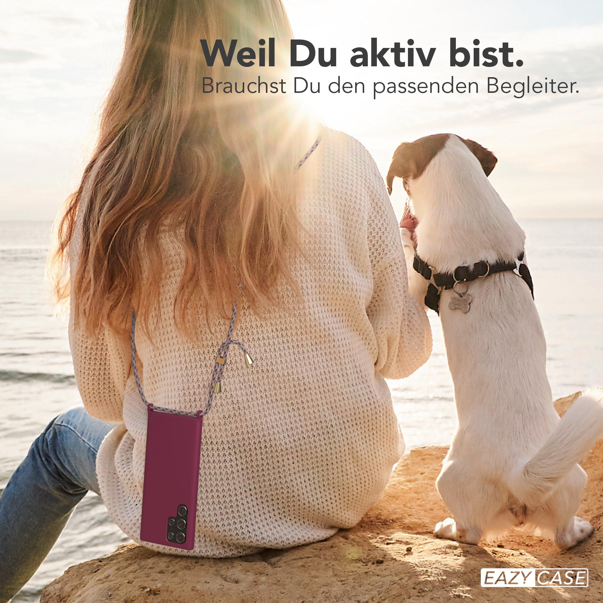 Frau mit Handyhülle am Meer, Hund schaut sie an. Text: Weil Du aktiv bist. Brauchst Du den passenden Begleiter.