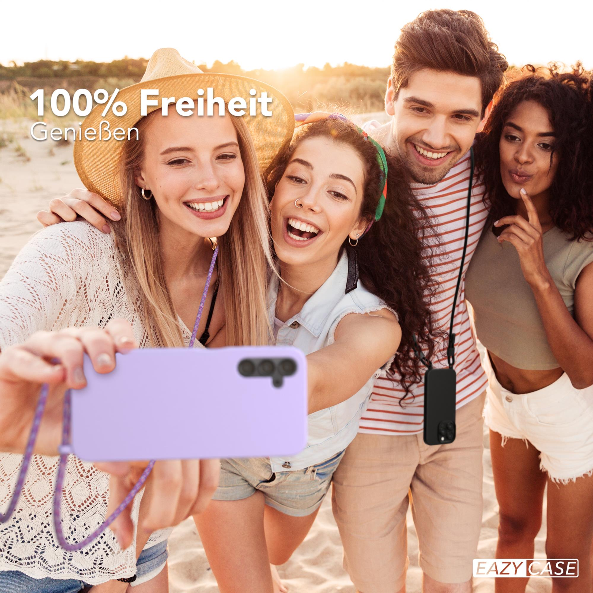 Vier Personen machen ein Selfie am Strand. Eine Person hält ein lila Telefon in einer Hülle mit Kordel.