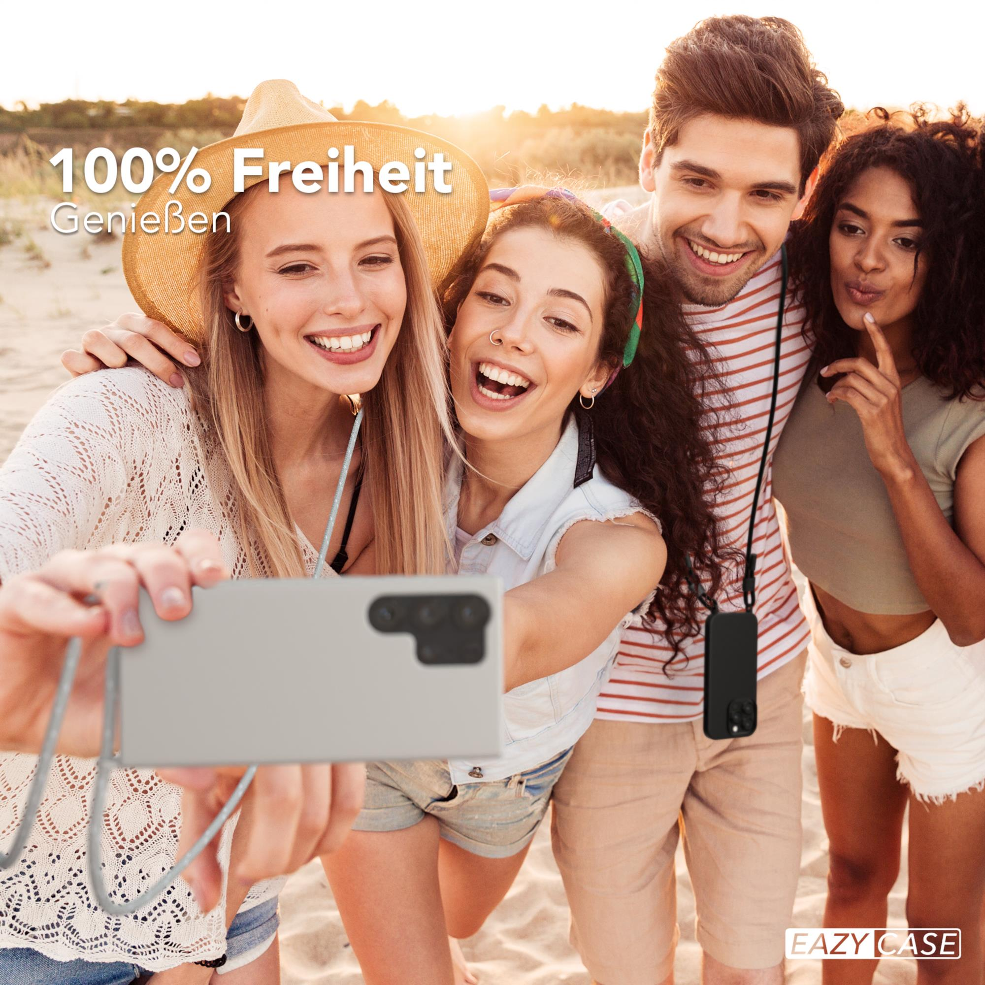 Eine Gruppe von vier Personen macht ein Selfie am Strand, lächelt, einer hält das Telefon.