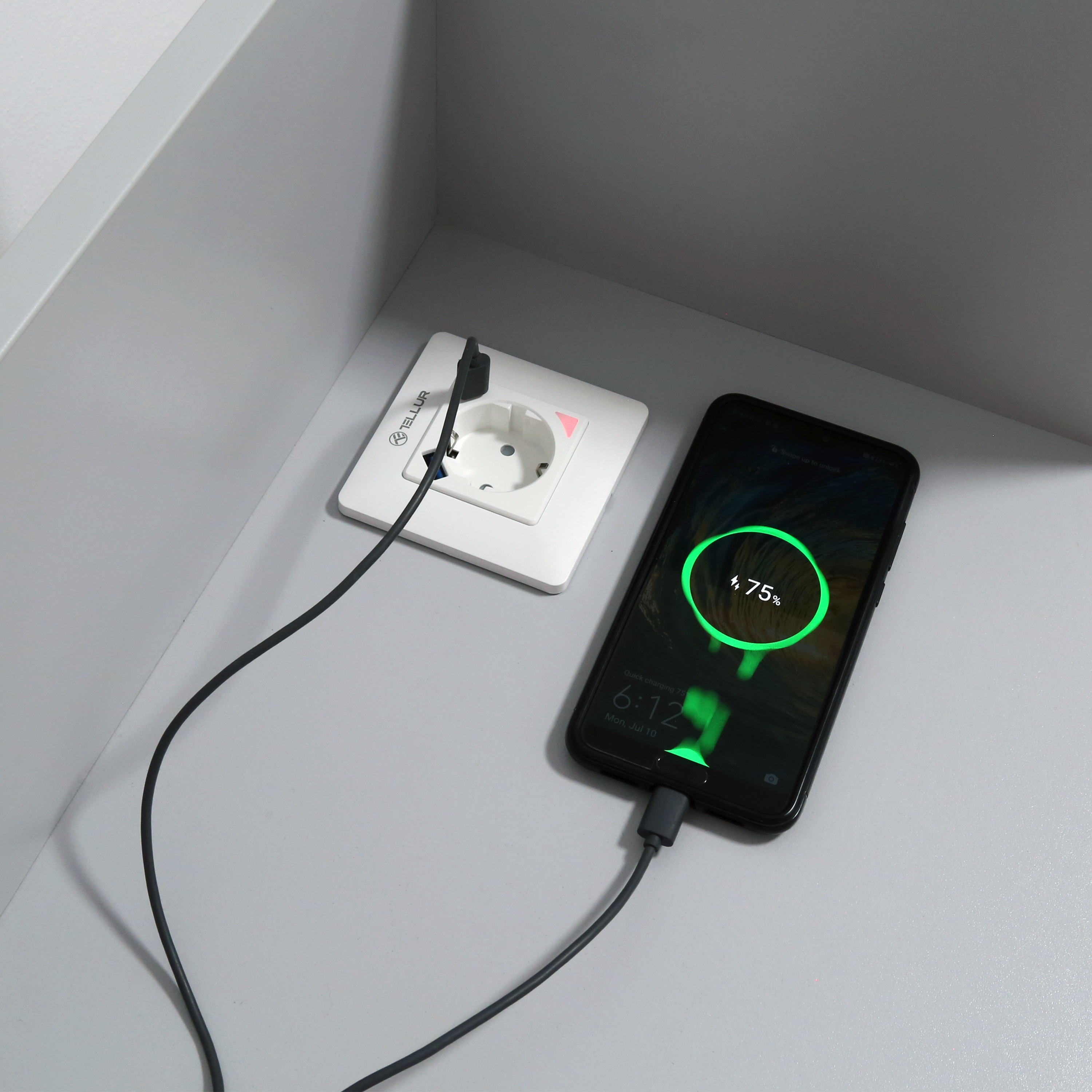 Telefon in der Nähe einer Steckdose laden. Telefon zeigt 75 % Akku an. Schwarzes Kabel am Telefon.